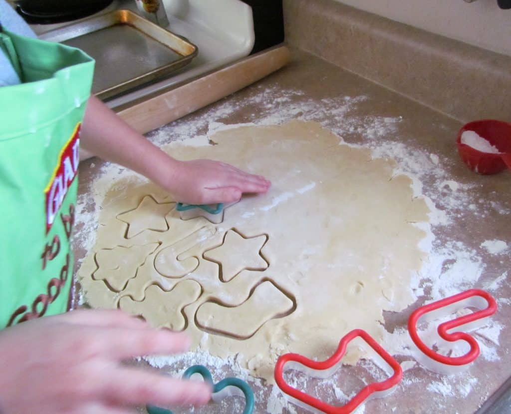a child pressing a cookie cutter into rolled out cookie dough