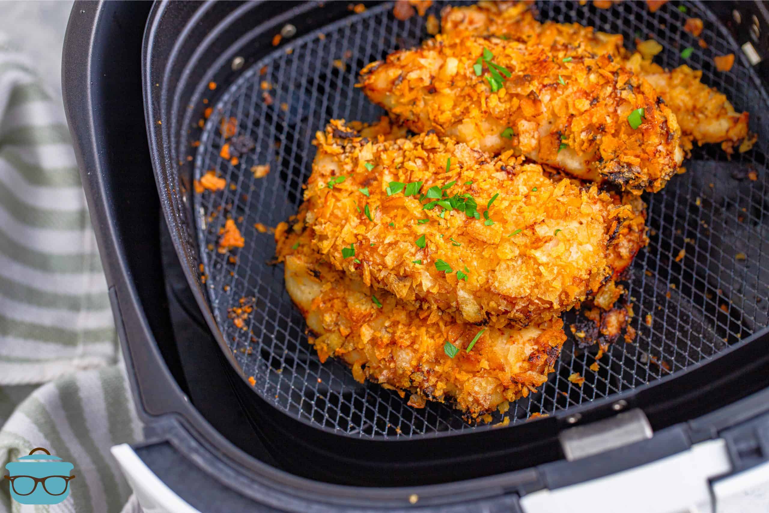 Crispy, fully cooked chicken tenders shown in the bottom of an air fryer basket.