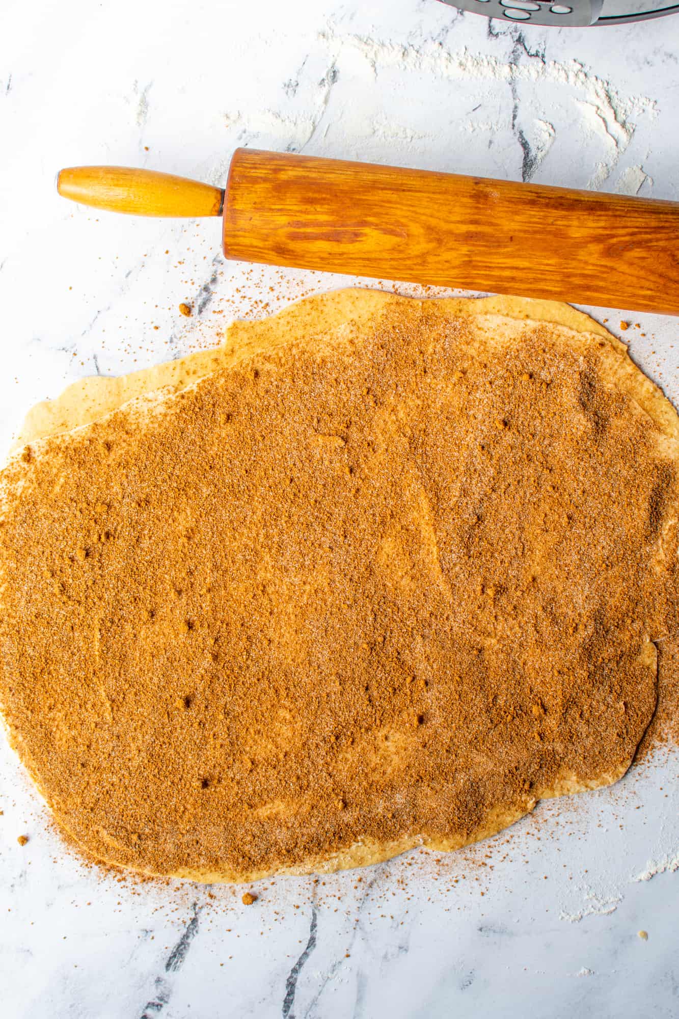 brown sugar cinnamon mixture sprinkled on top of butter on cinnamon roll dough