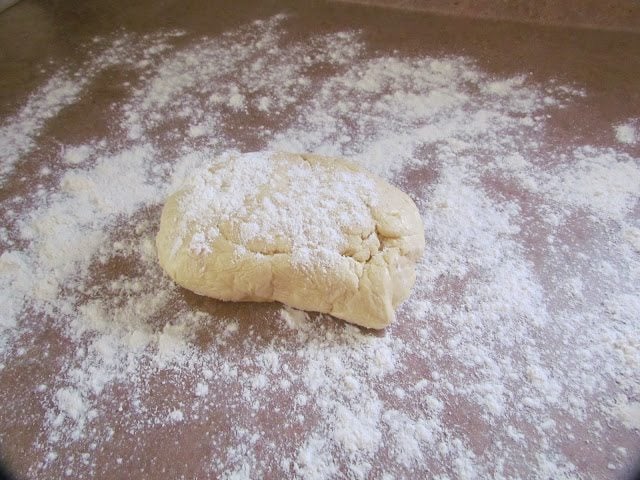 sugar cookie dough ball on flour covered surface and dough ball also covered in flour