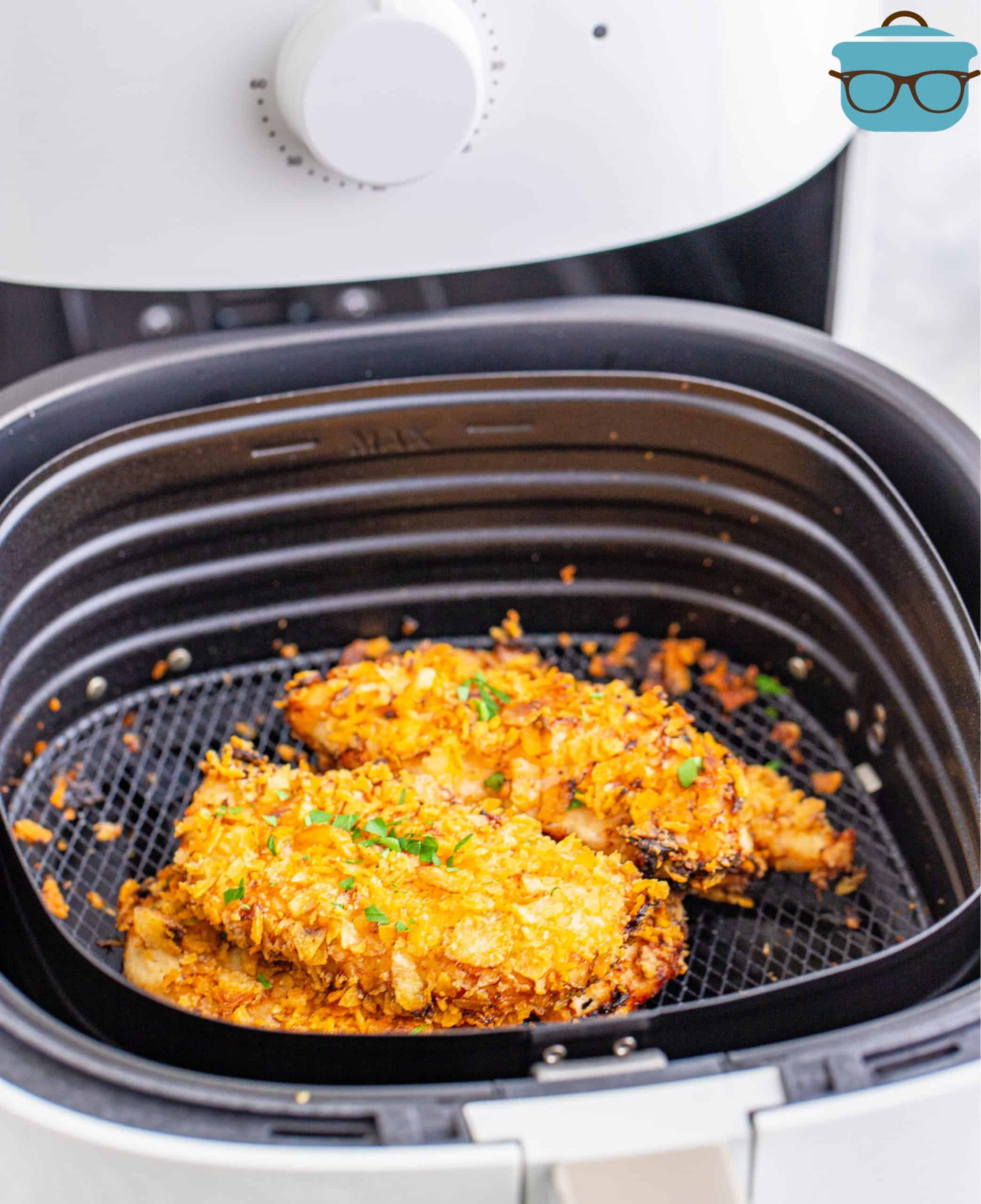 Fully cooked air fryer potato chip coated chicken tenders in an air fryer basket.