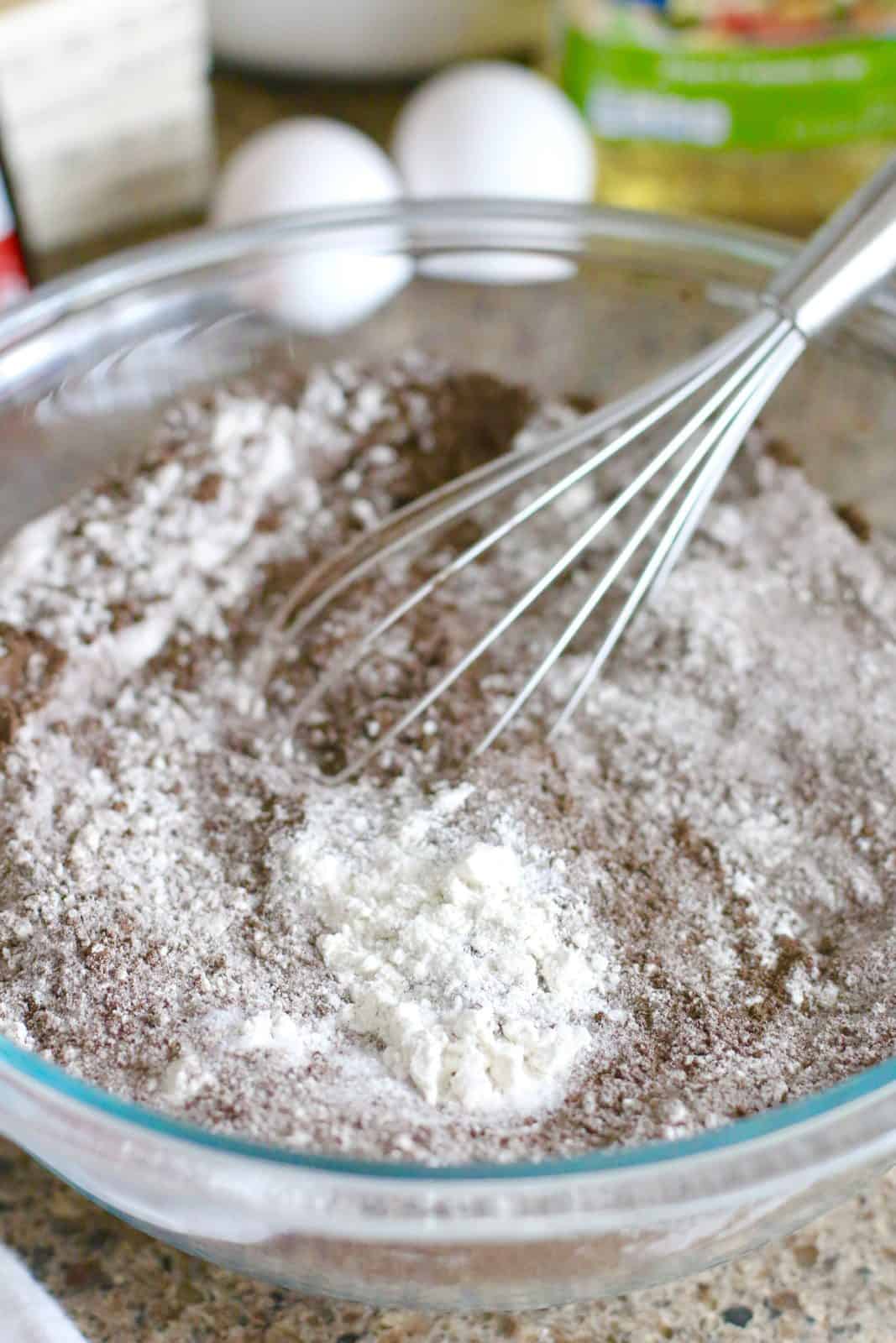 flour, sugar, dark chocolate cocoa powder, baking soda, baking powder whisked in a clear bowl.
