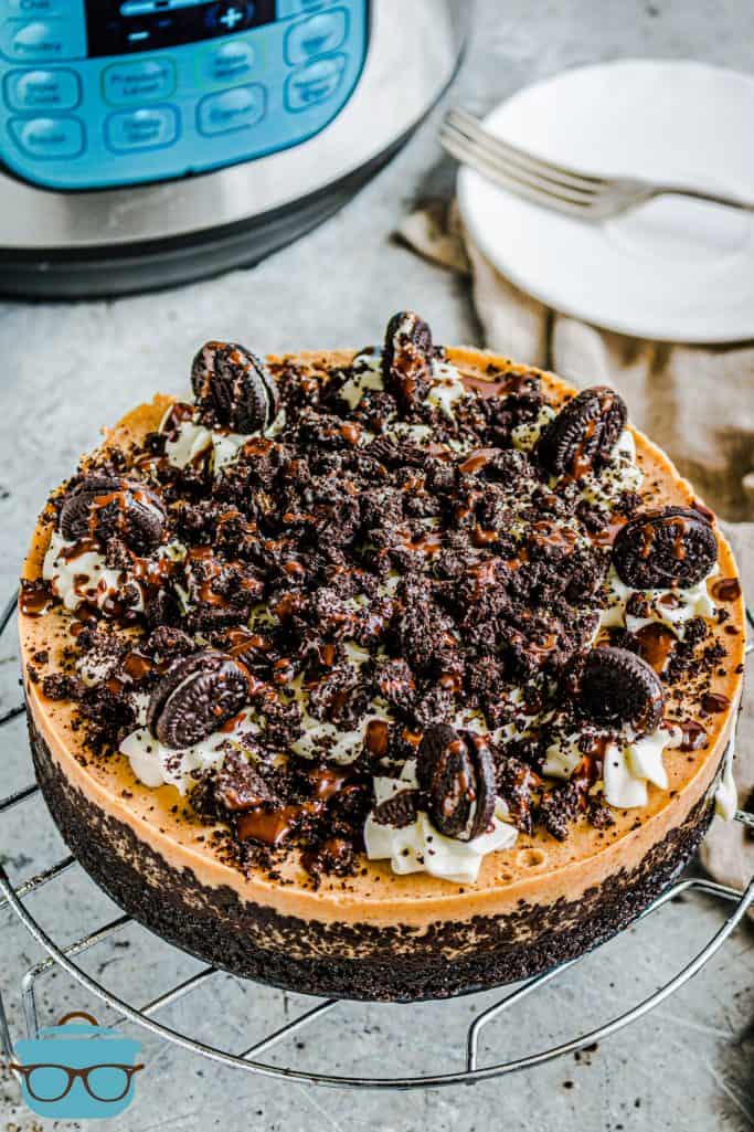 Instant Pot Oreo Pumpkin Cheesecake, fully baked and decorated on top of a cooling rack