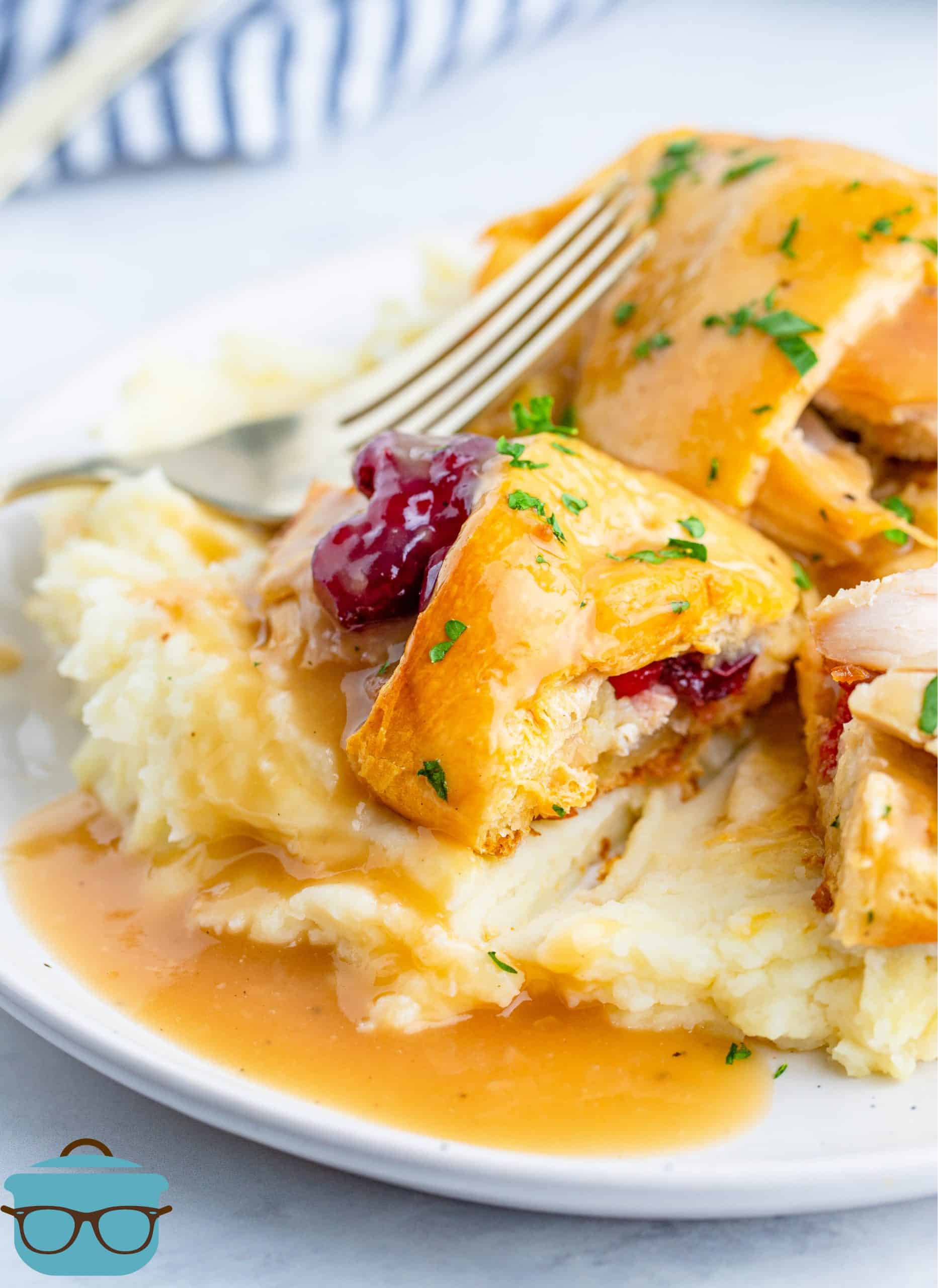 Turkey and Stuffing Crescent Roll Bundles served on top of mashed potatoes with gravy on top.