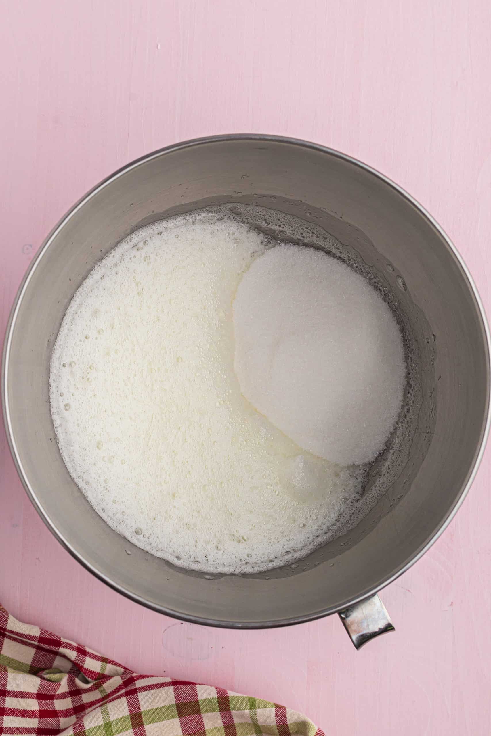 sugar added to egg whites in a mixing bowl.