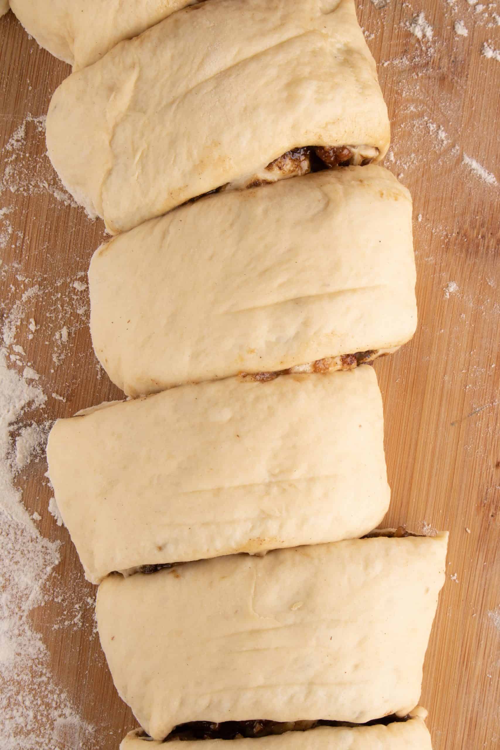 sliced cinnamon roll dough on a wooden surface