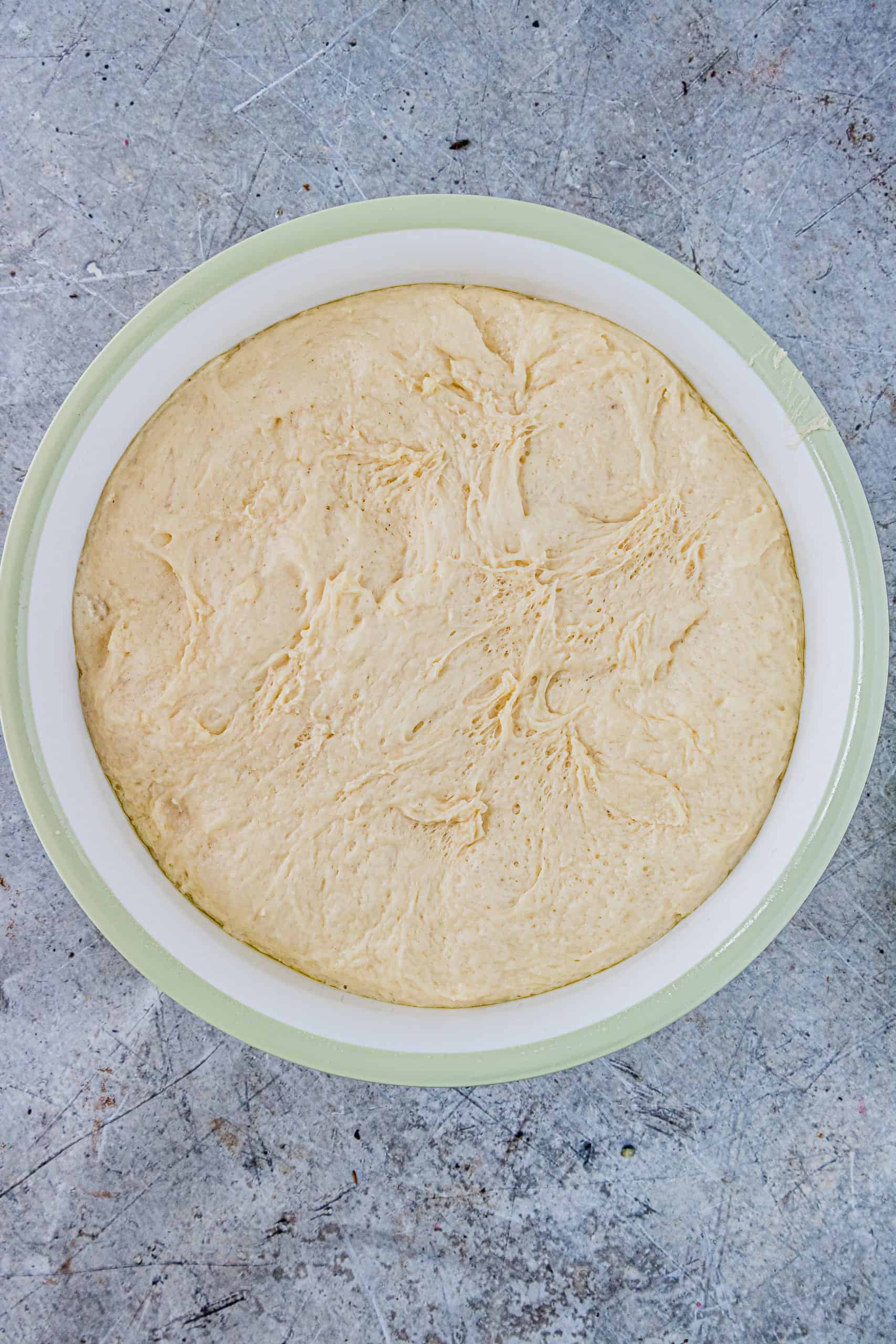 cinnamon roll yeast dough after it has increased in size in a large white bowl