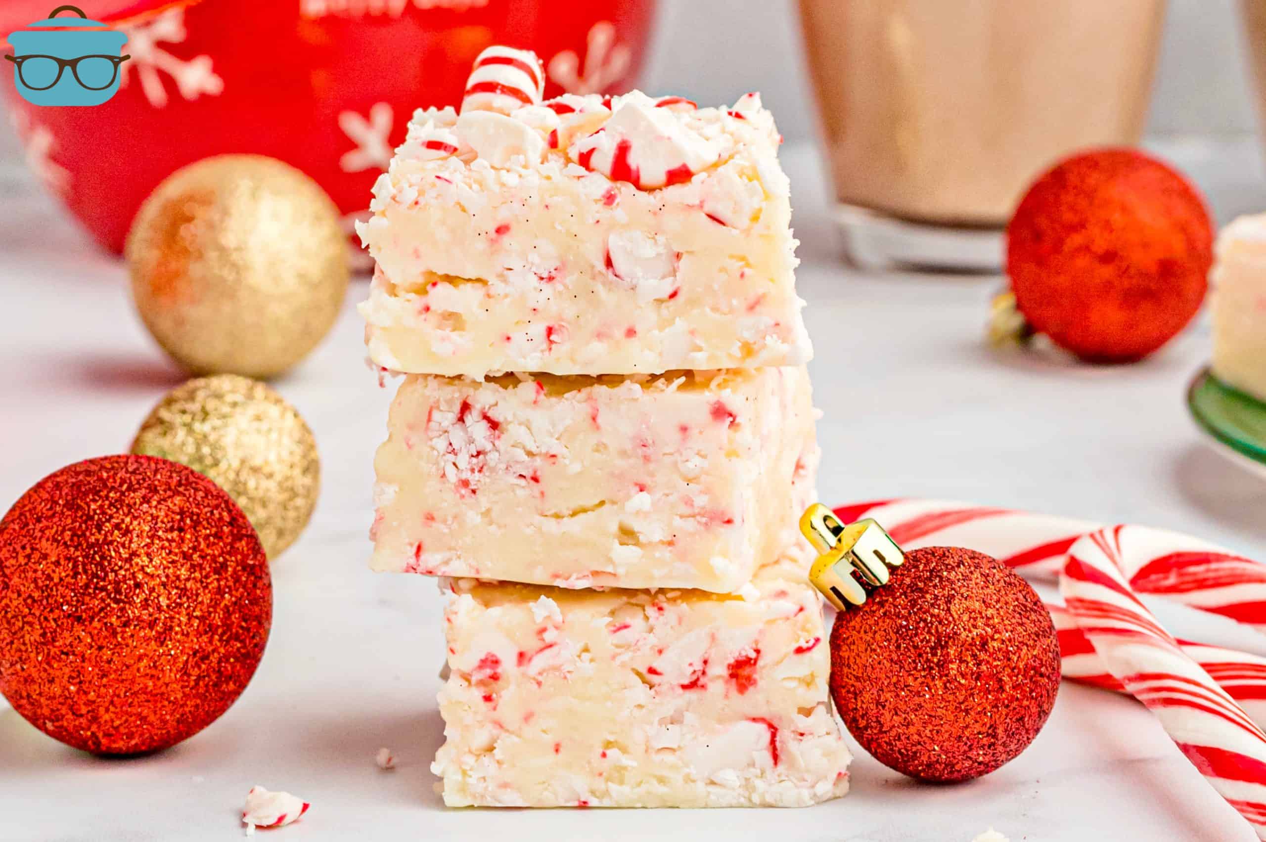 stacked peppermint fudge pieces with small Christmas tree ornaments scattered around