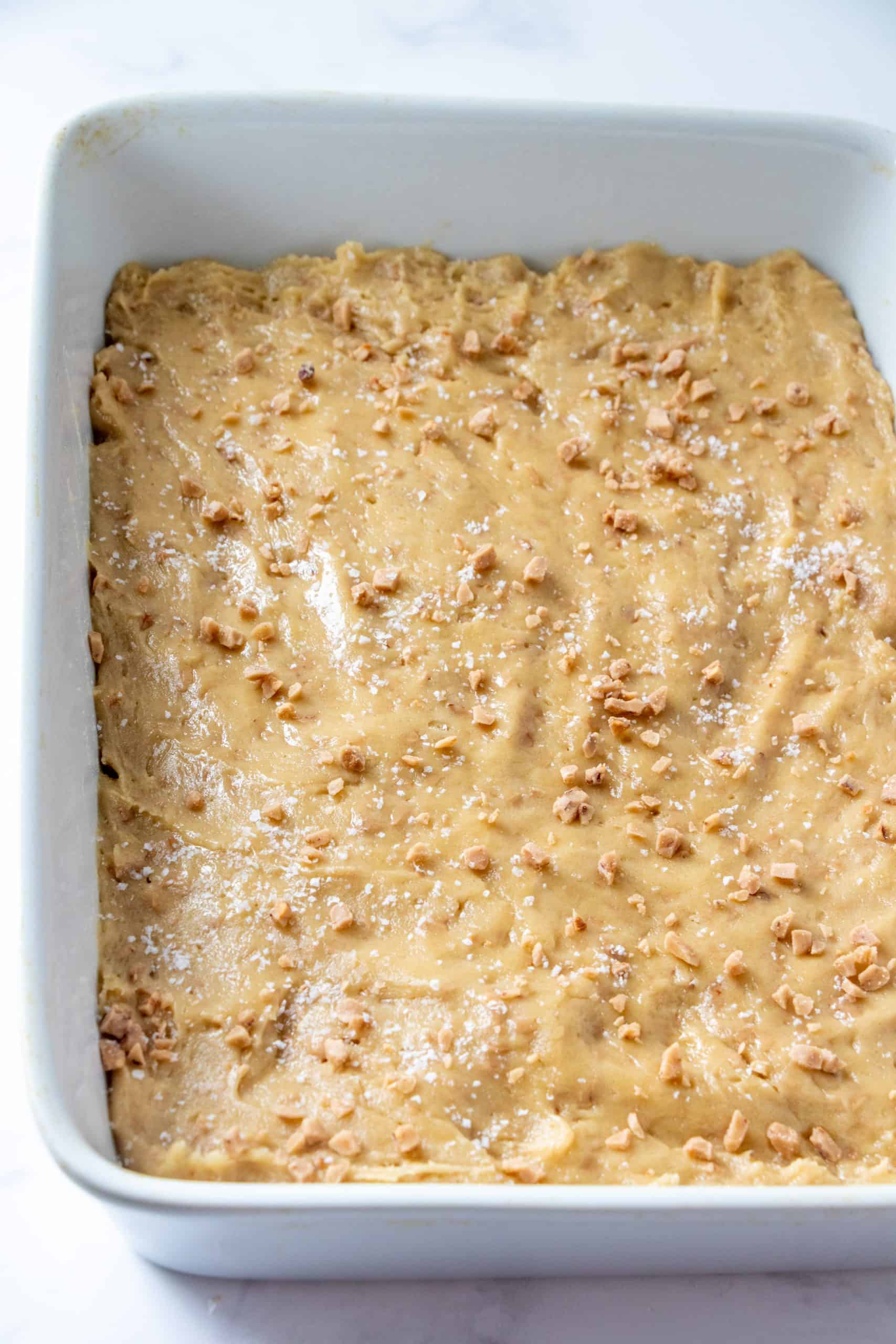 blondie batter spread out evenly into white baking dish.