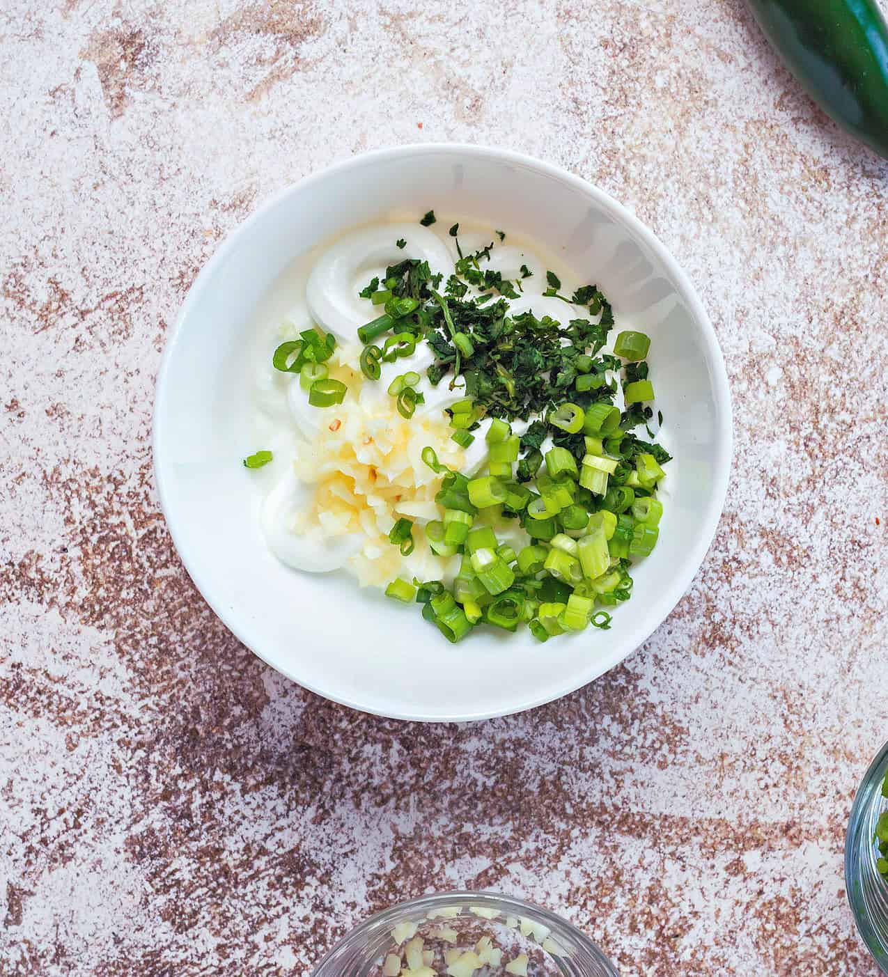 green onion, cilantro and garlic mixed together with sour cream in a small bowl.