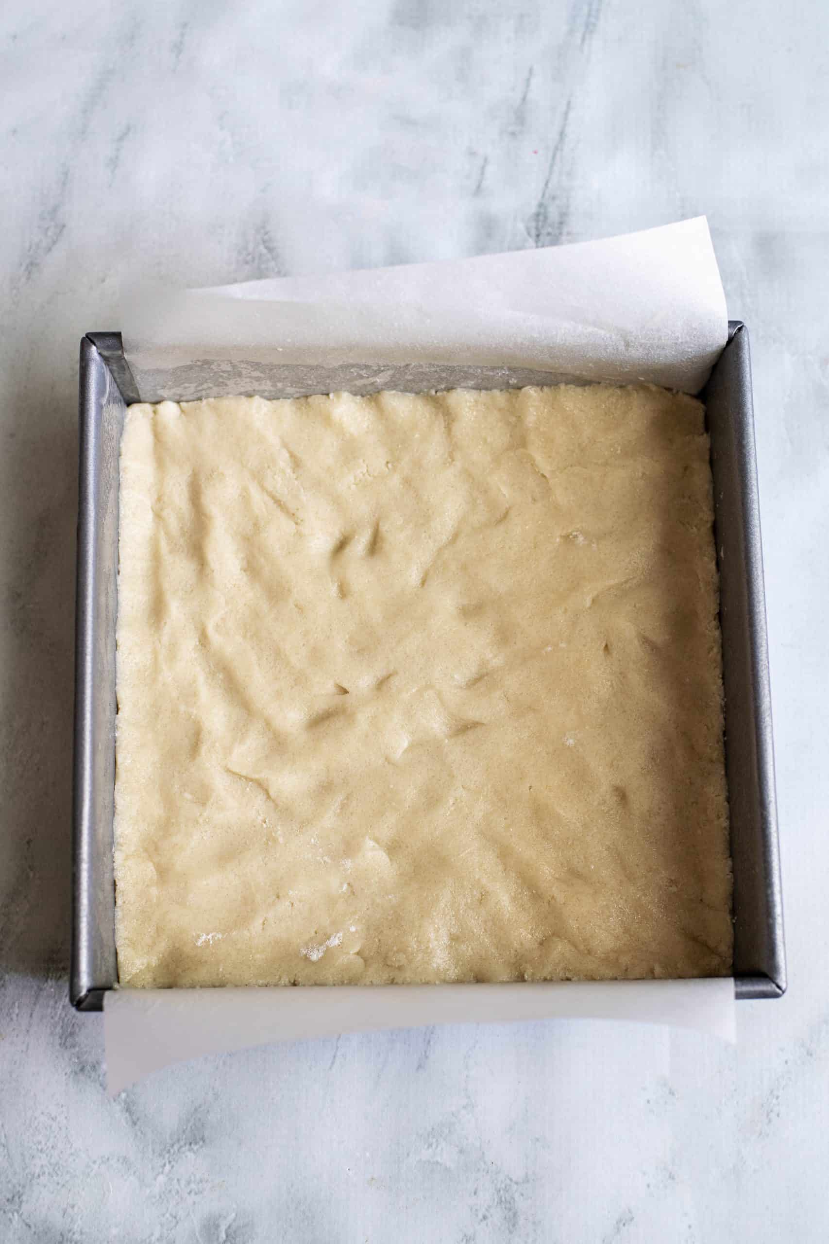sugar cookie dough pressed into the bottom of a square baking dish.