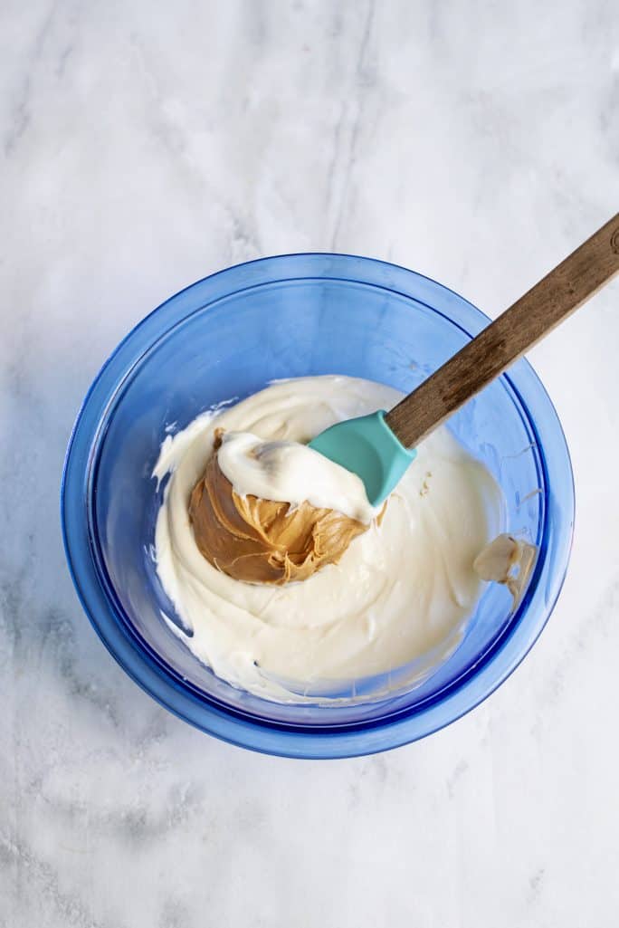 mexendo a manteiga de amendoim no chocolate branco derretido em uma tigela azul