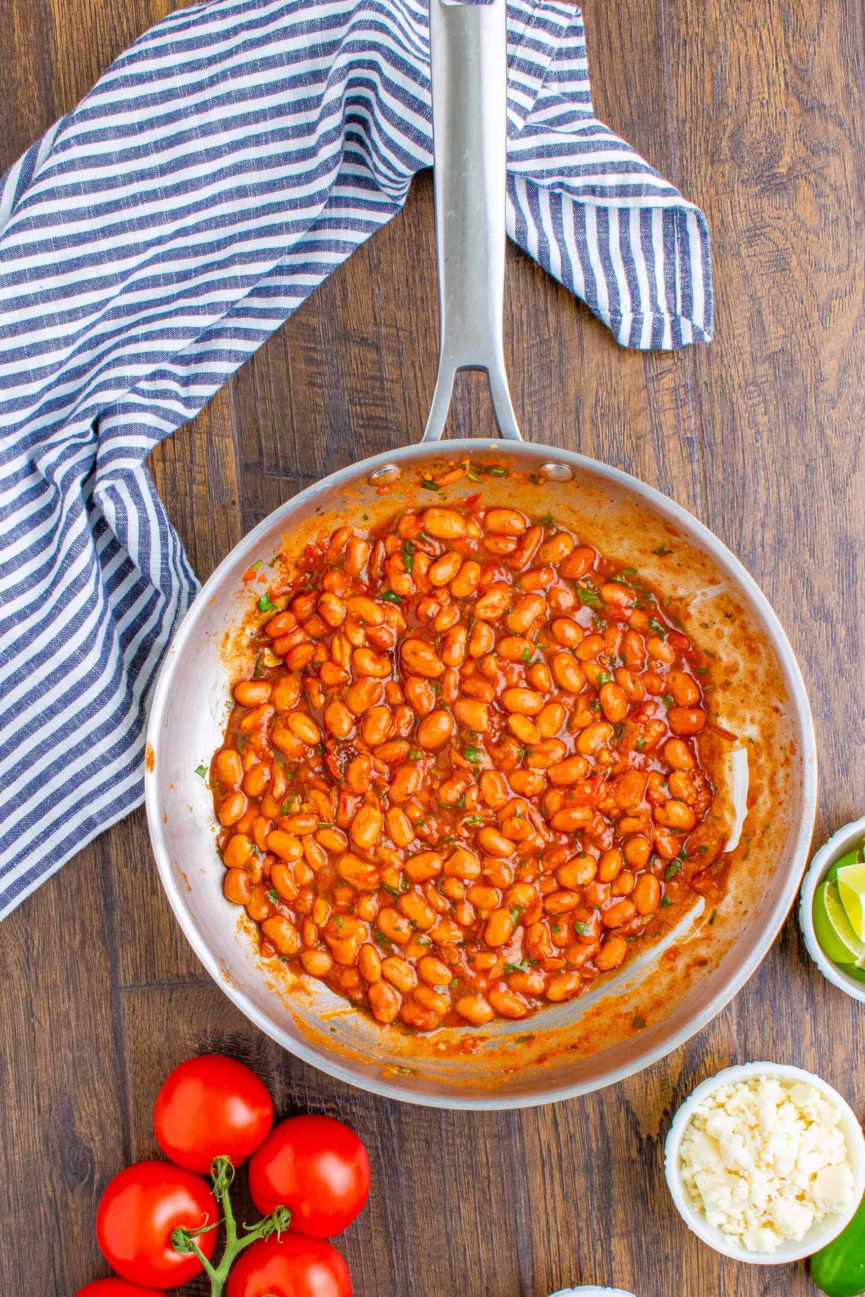 simmered taco seasoned pinto beans in a stainless steel, medium sized skillet.