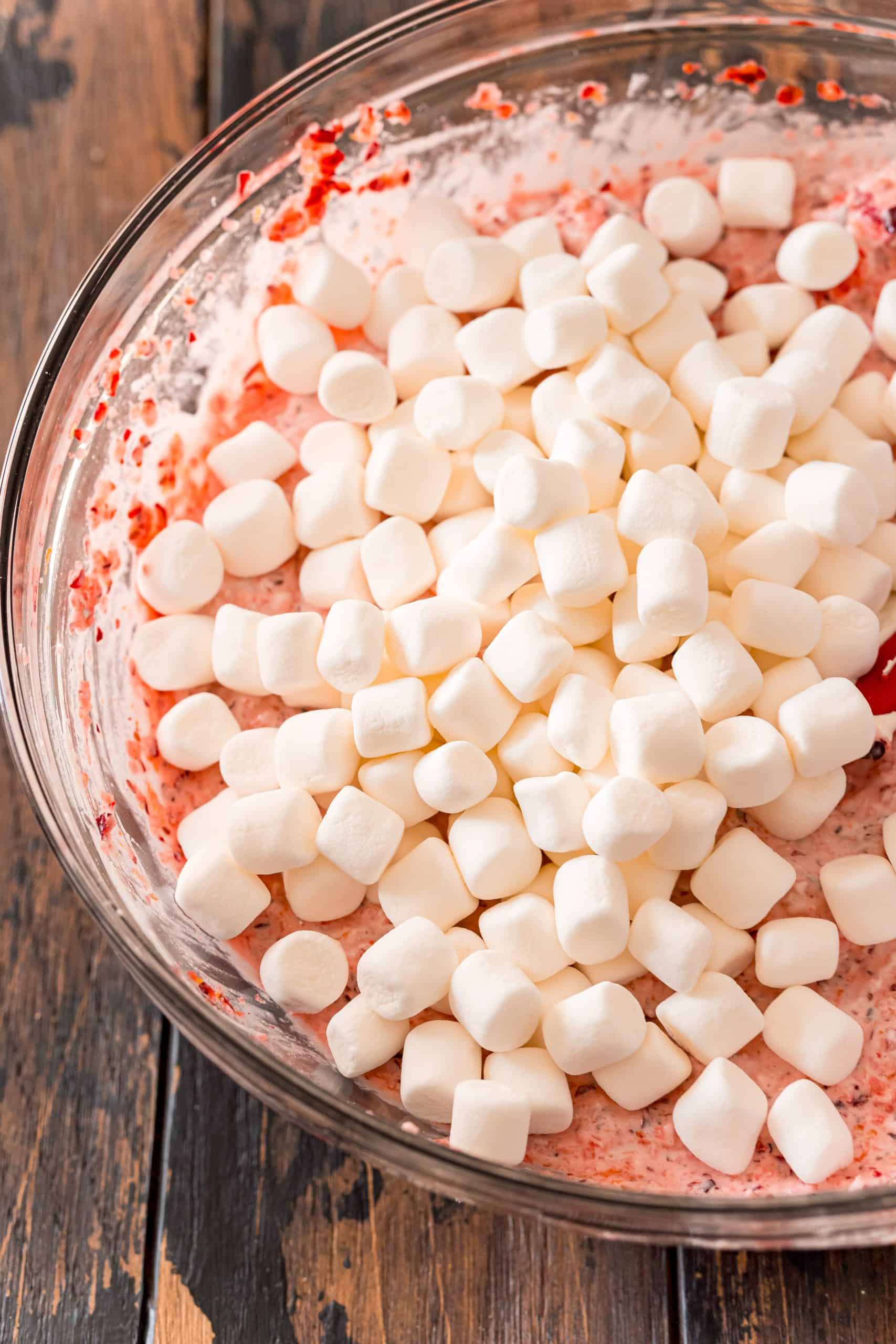 mini marshmallows added to cranberry fluff mixture in a clear bowl.