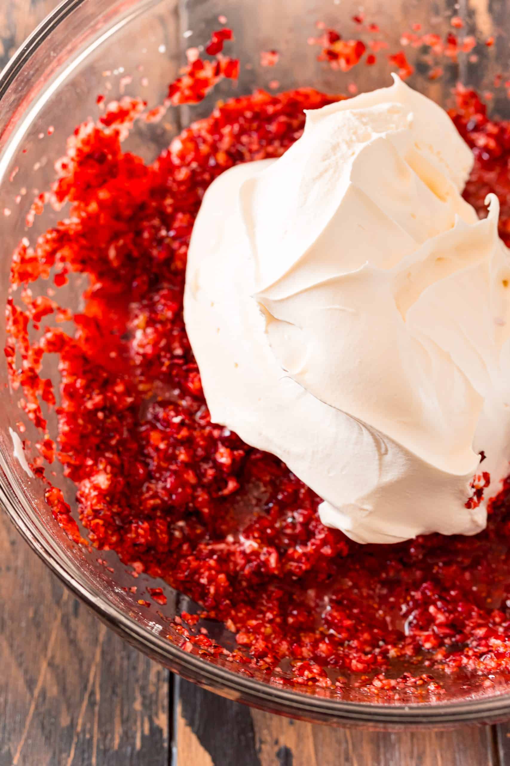 whipped topping and orange zest added to cranberry relish mixture in a bowl.