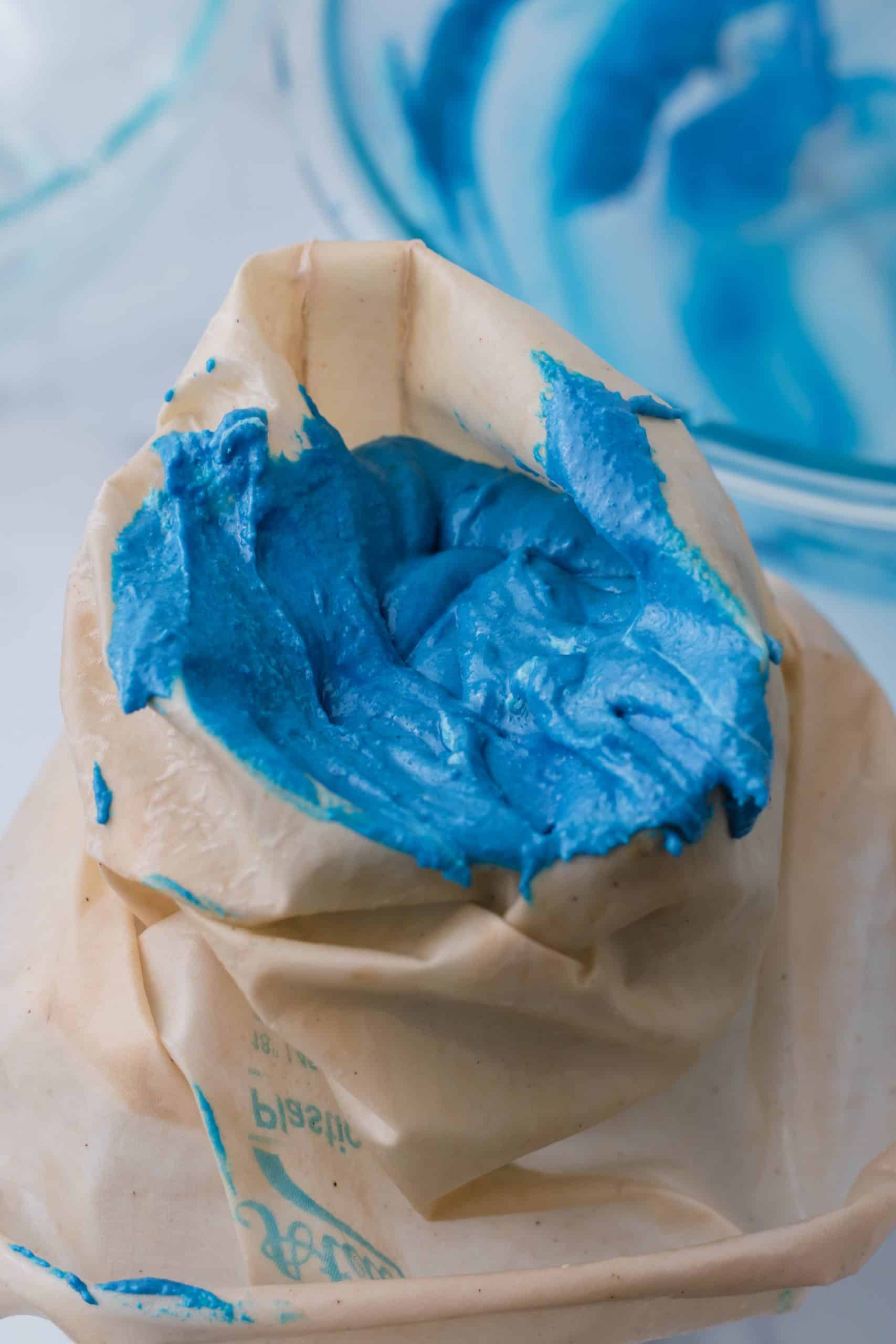 adding blue macaron batter in a natural color piping bag.