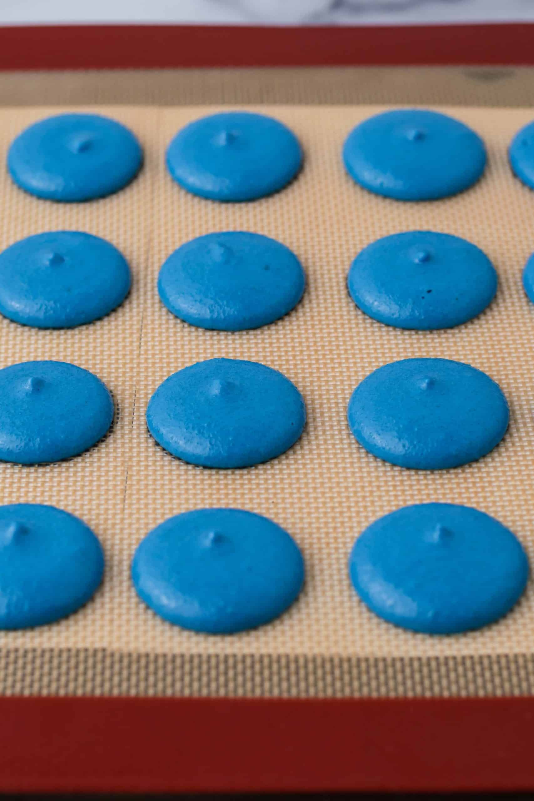 blue macarons on a baking mat.