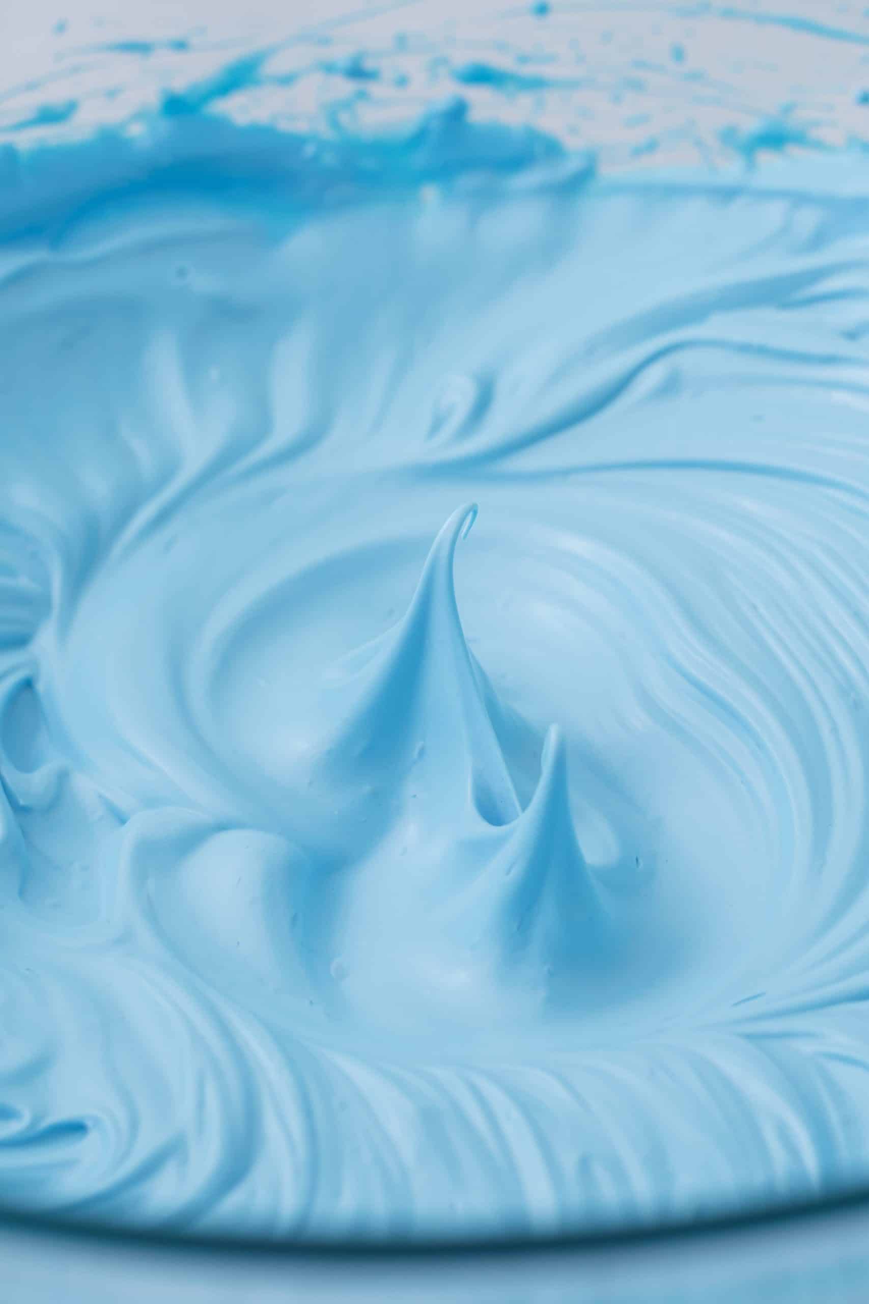 thick blue whipped egg whites in a clear bowl.
