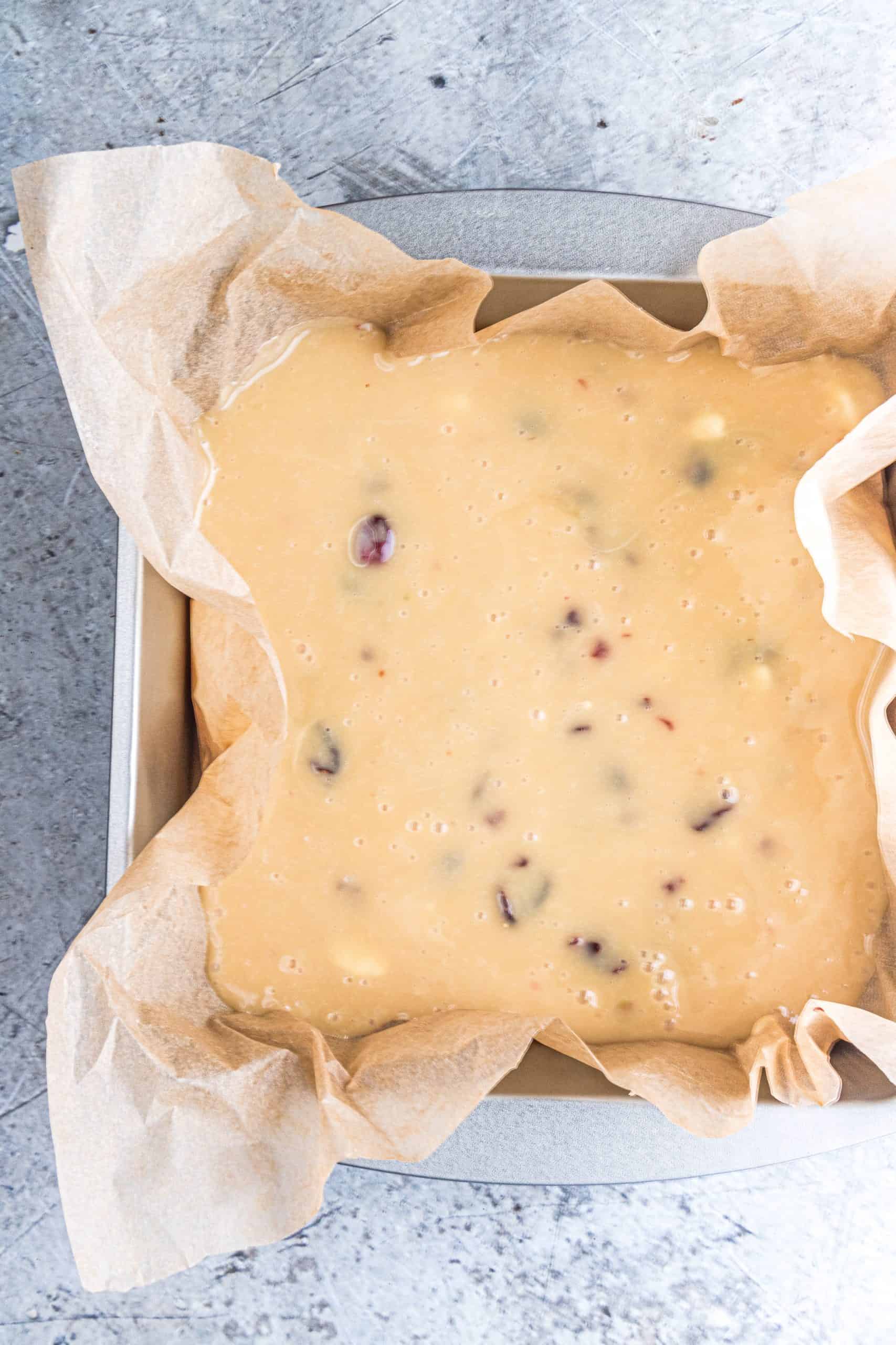 white chocolate fudge batter poured into a parchment paper lined baking pan.