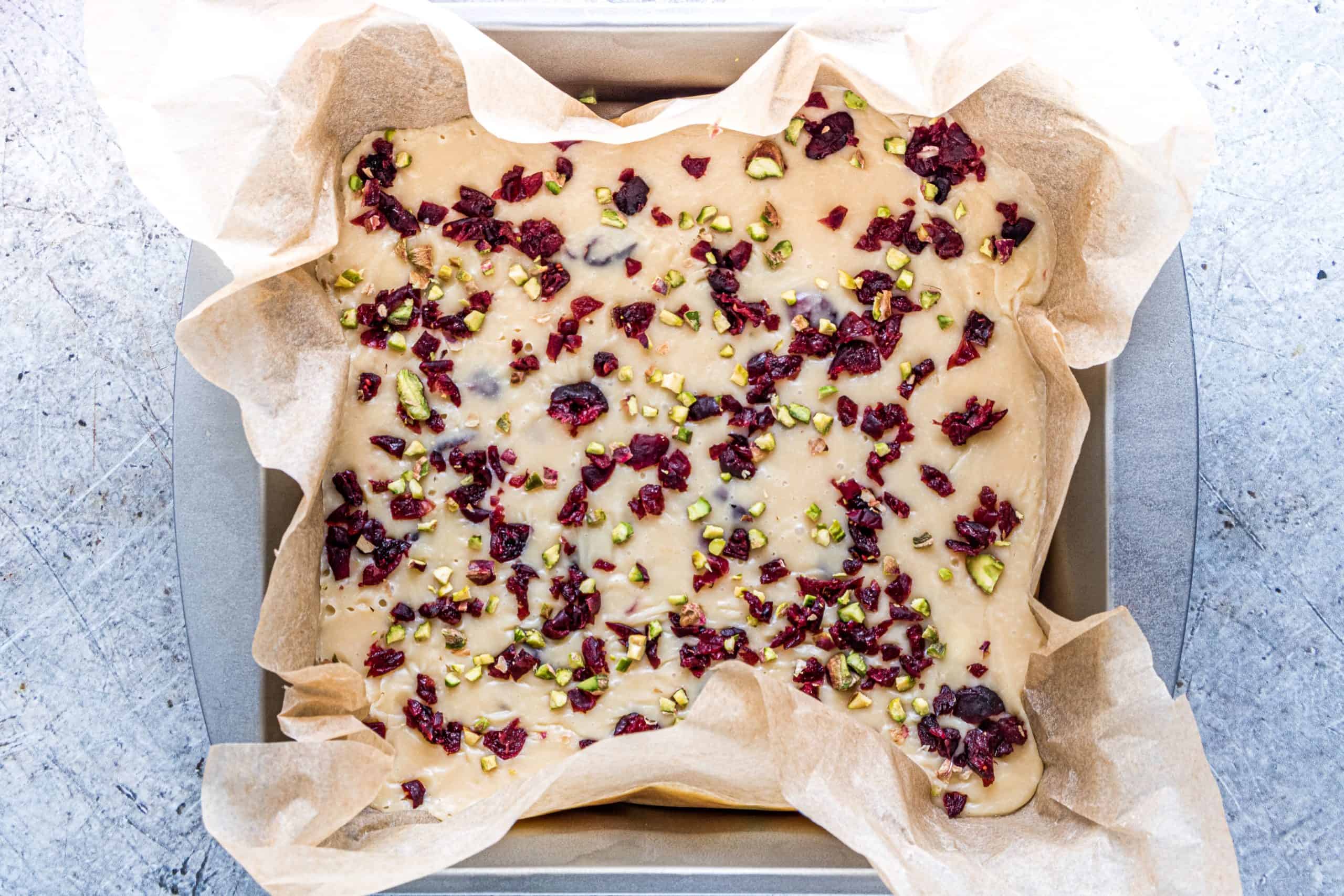 dried cranberries and pistachios sprinkled on top of white chocolate fudge mixture.