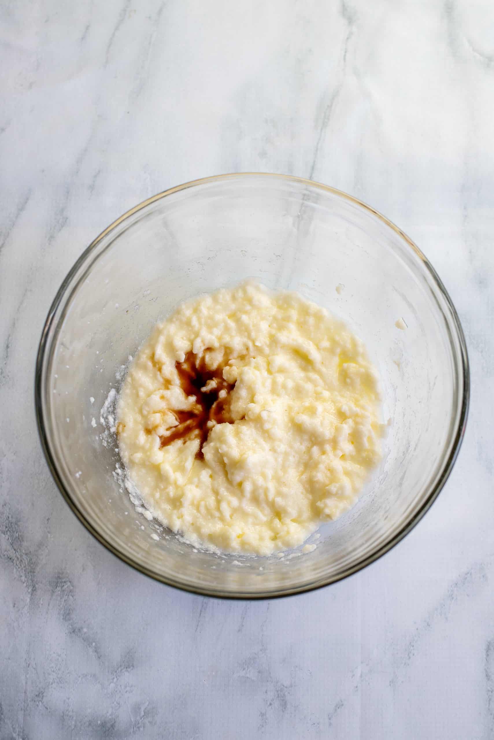 vanilla extract added to creamed butter and sugar mixture in a clear bowl.