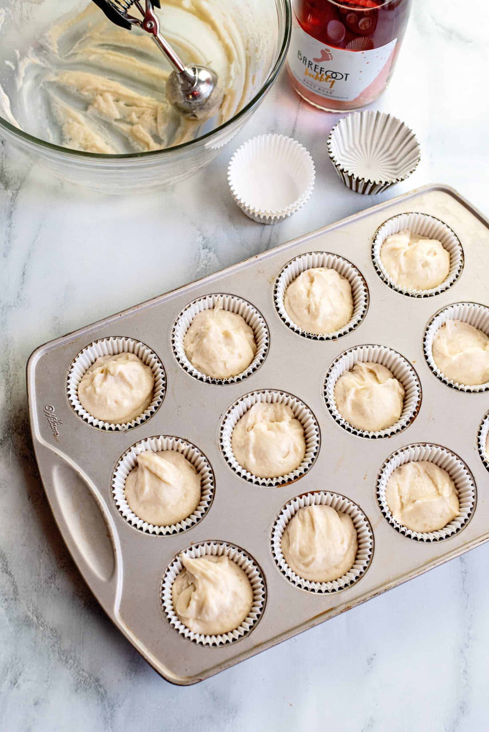champagne cupcake batter added to paper liners in a 12-cup cupcake pan.