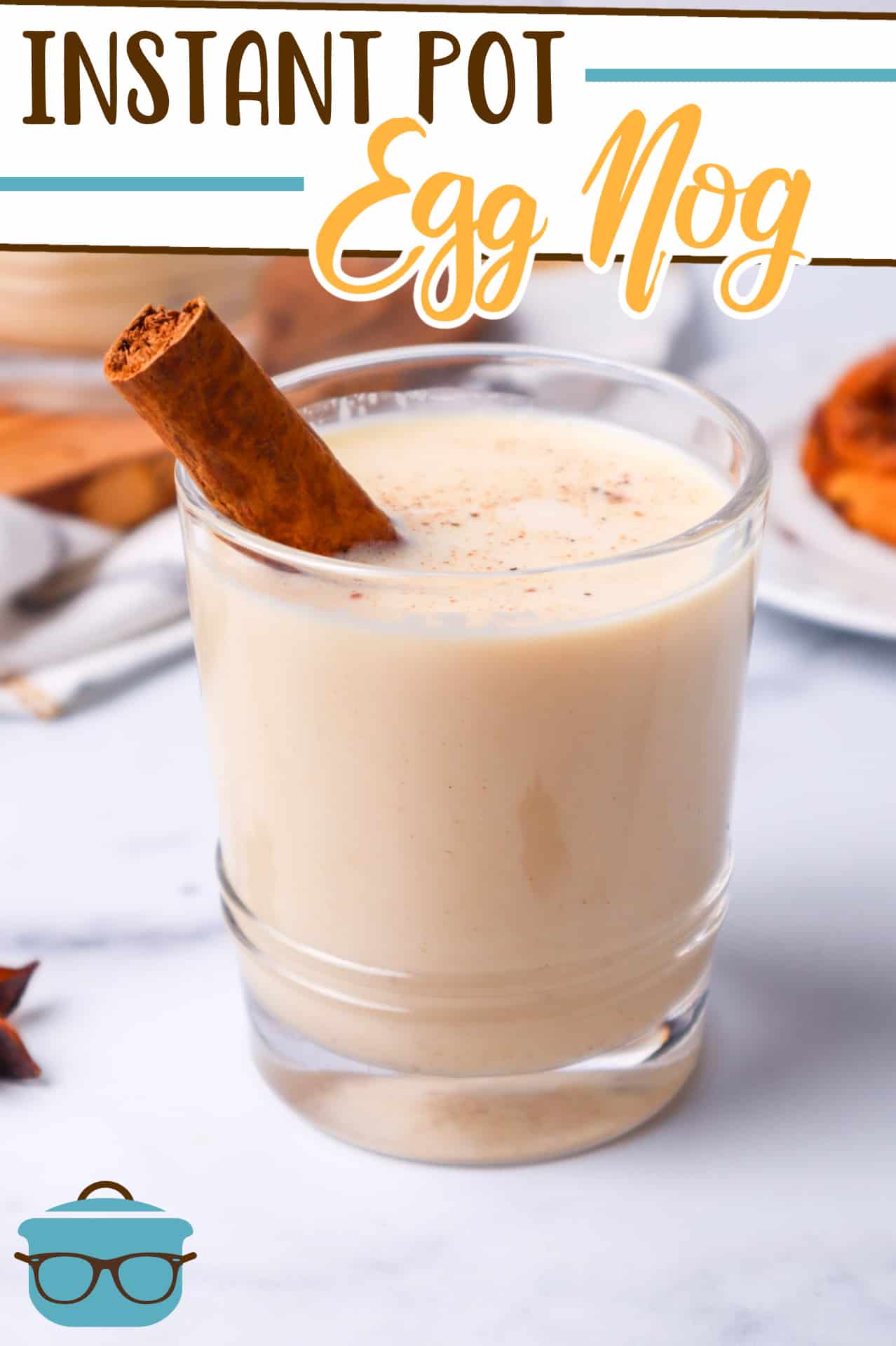 Instant Pot Egg Nog recipe from The Country Cook, pictured in a small glass with a cinnamon stick, shown on a marble surface.