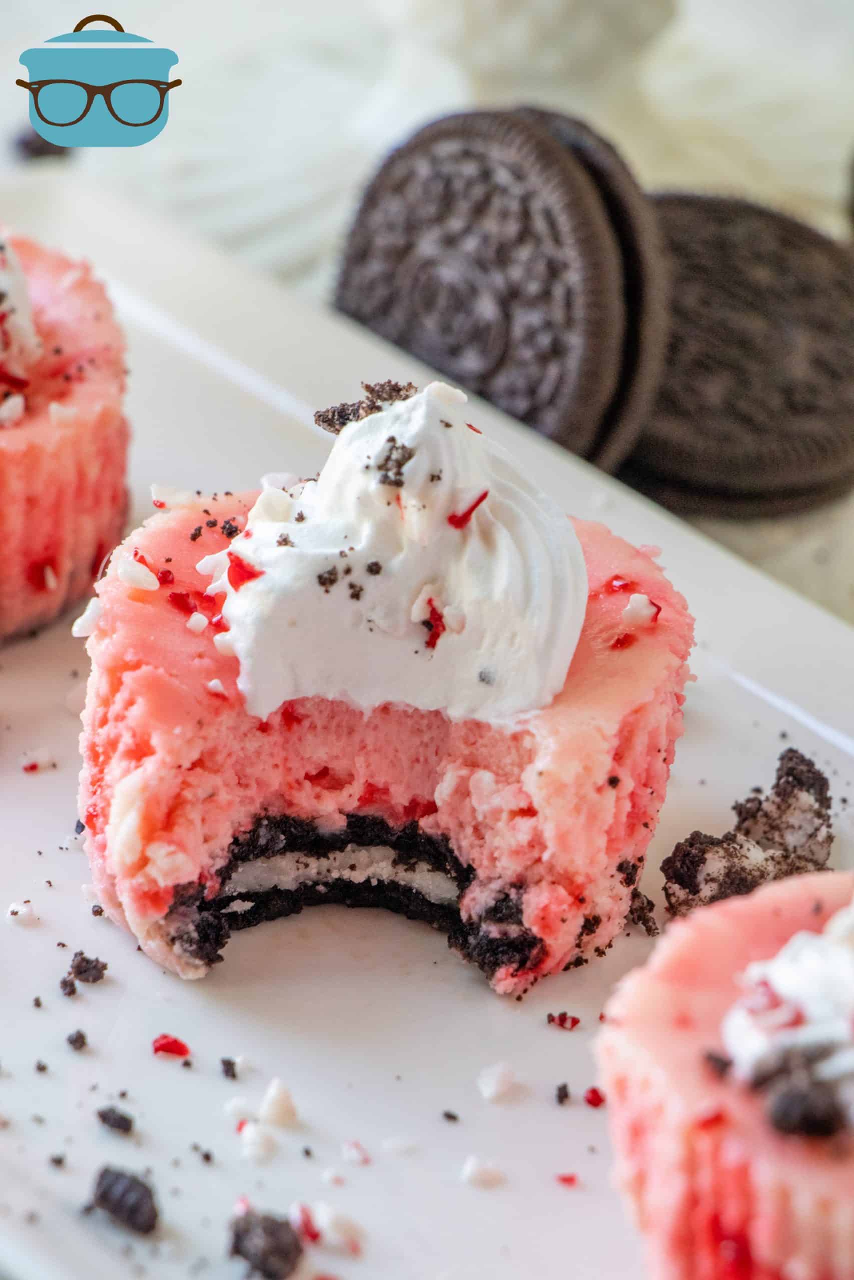 a mini cheesecake with a bite removed to seee the Oreo and peppermint cheesecake middle.