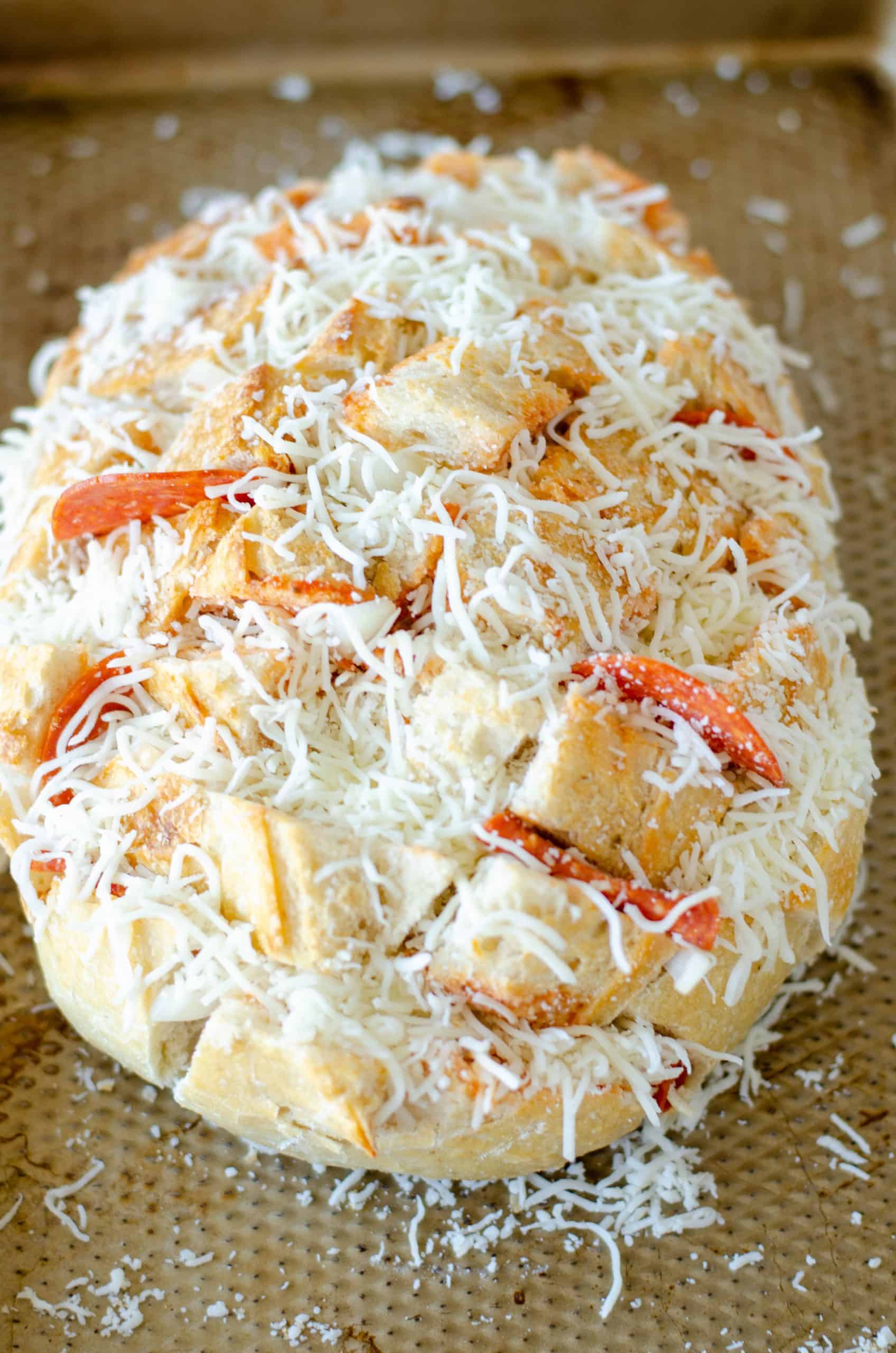 shredded mozzarella cheese stuffed inside sliced sourdough bread on a baking sheet.