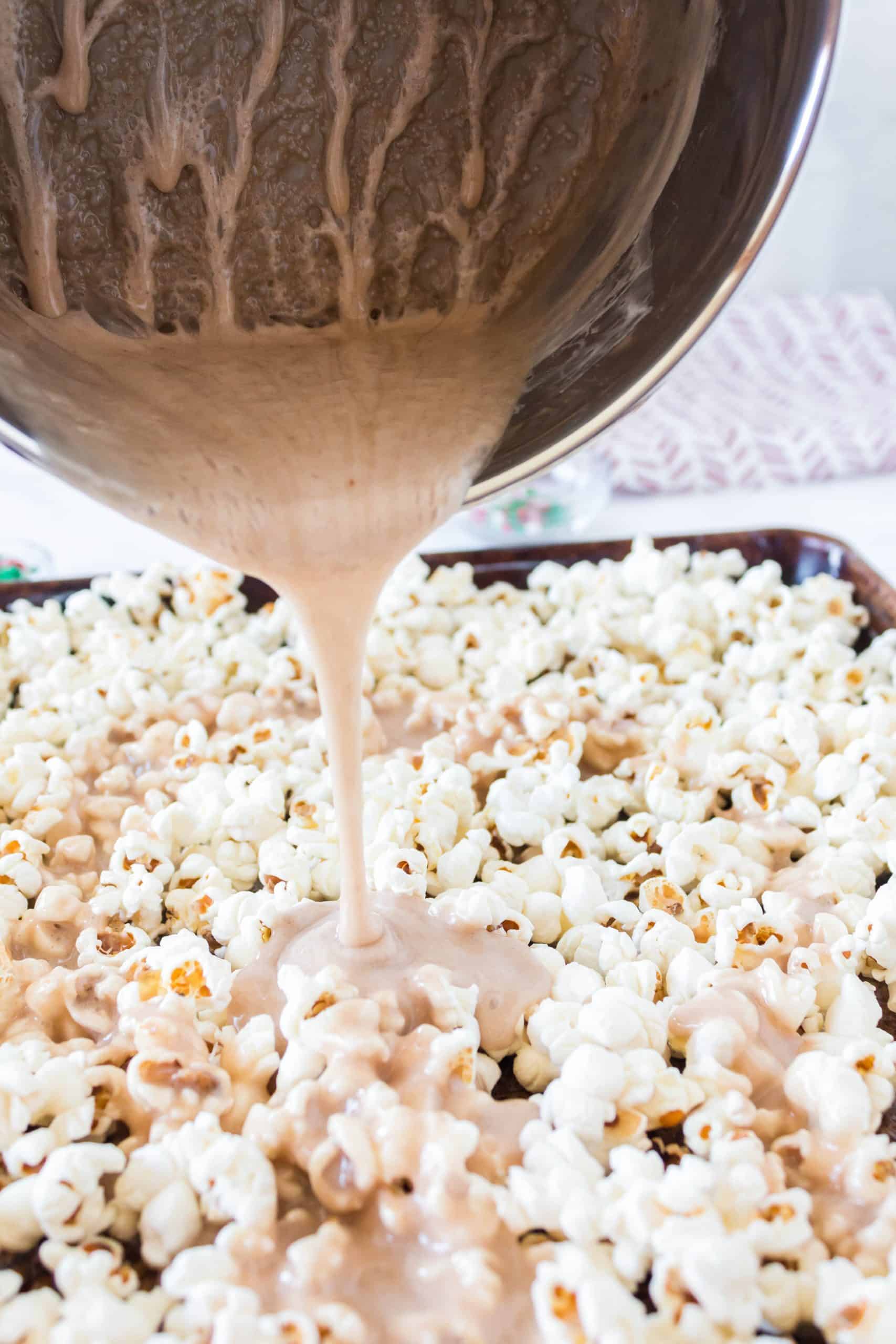 pouring melted marshmallow mixture from a sauce pan onto popped popcorn.
