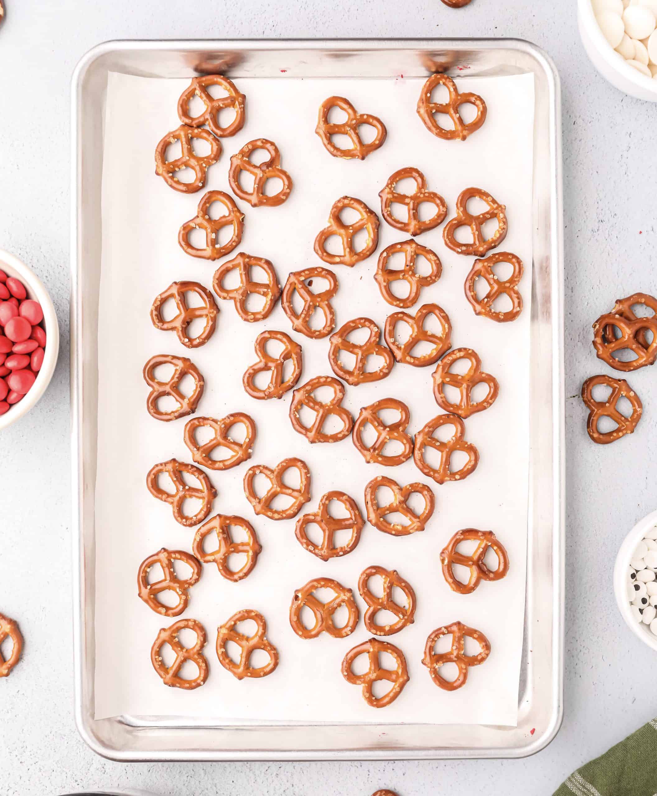 mini pretzels arranged in a single layer on a parchment lined baking sheet.