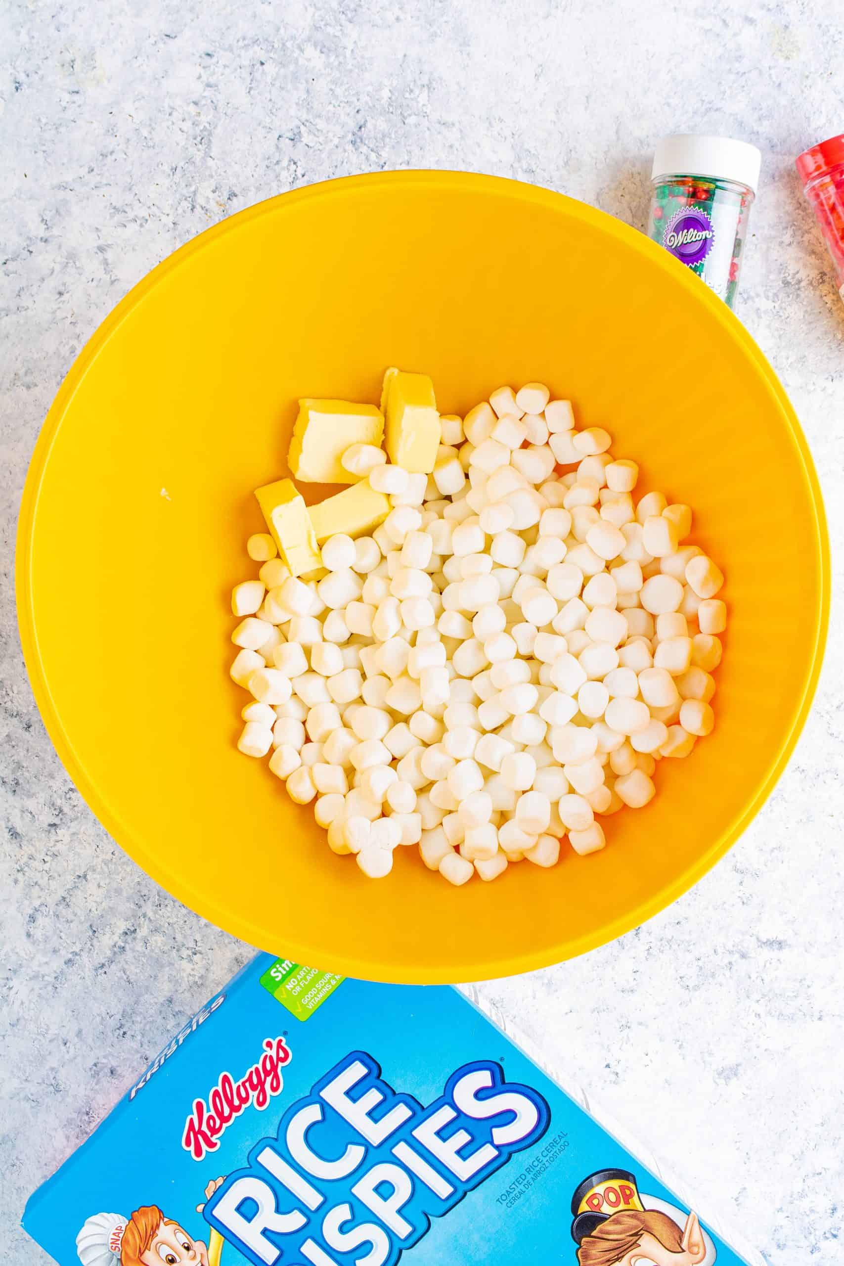 mini marshmallows and butter in the bottom of a large yellow bowl.