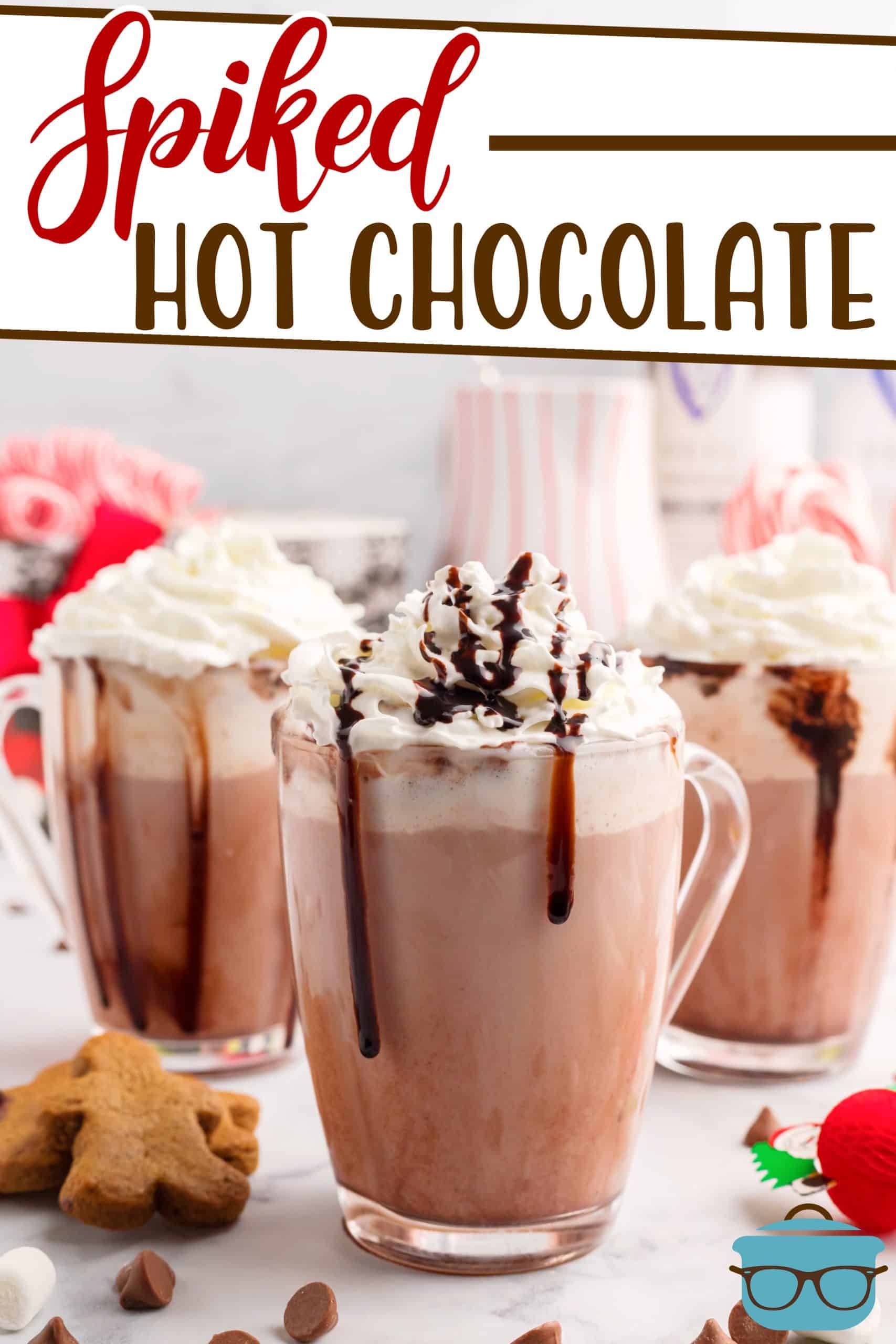 Spiked Hot Chocolate recipe from The Country Cook, hot chocolate shown in clear mugs and topped with whipped cream and drizzles with chocolate syrup.