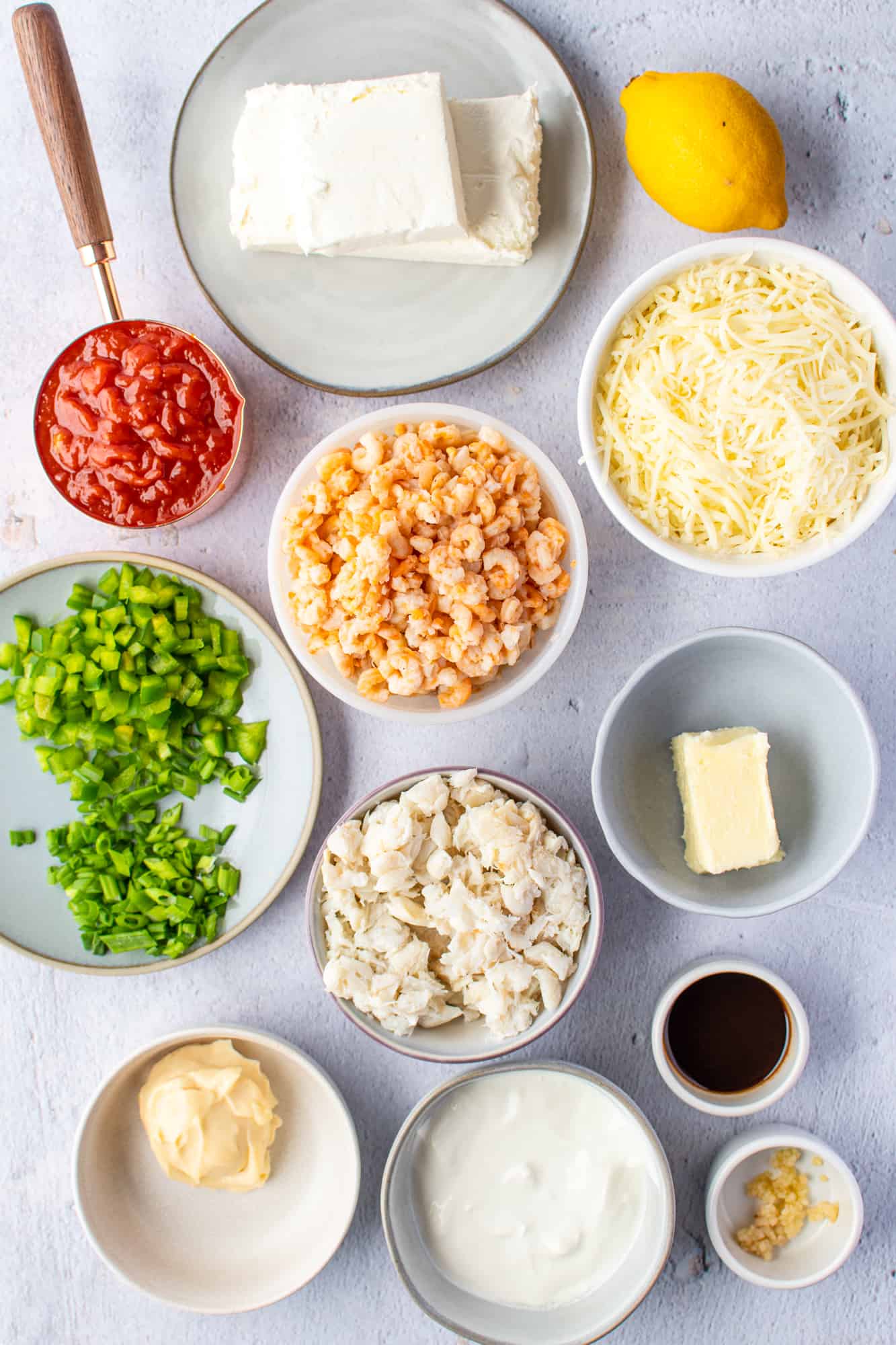 cream cheese, sour cream, mayonnaise, unsalted butter, Worcestershire sauce, a fresh lemon, minced garlic, cocktail sauce, lump crab meat, tiny shrimp, shredded Mozzarella cheese, sliced green onions, diced green pepper.