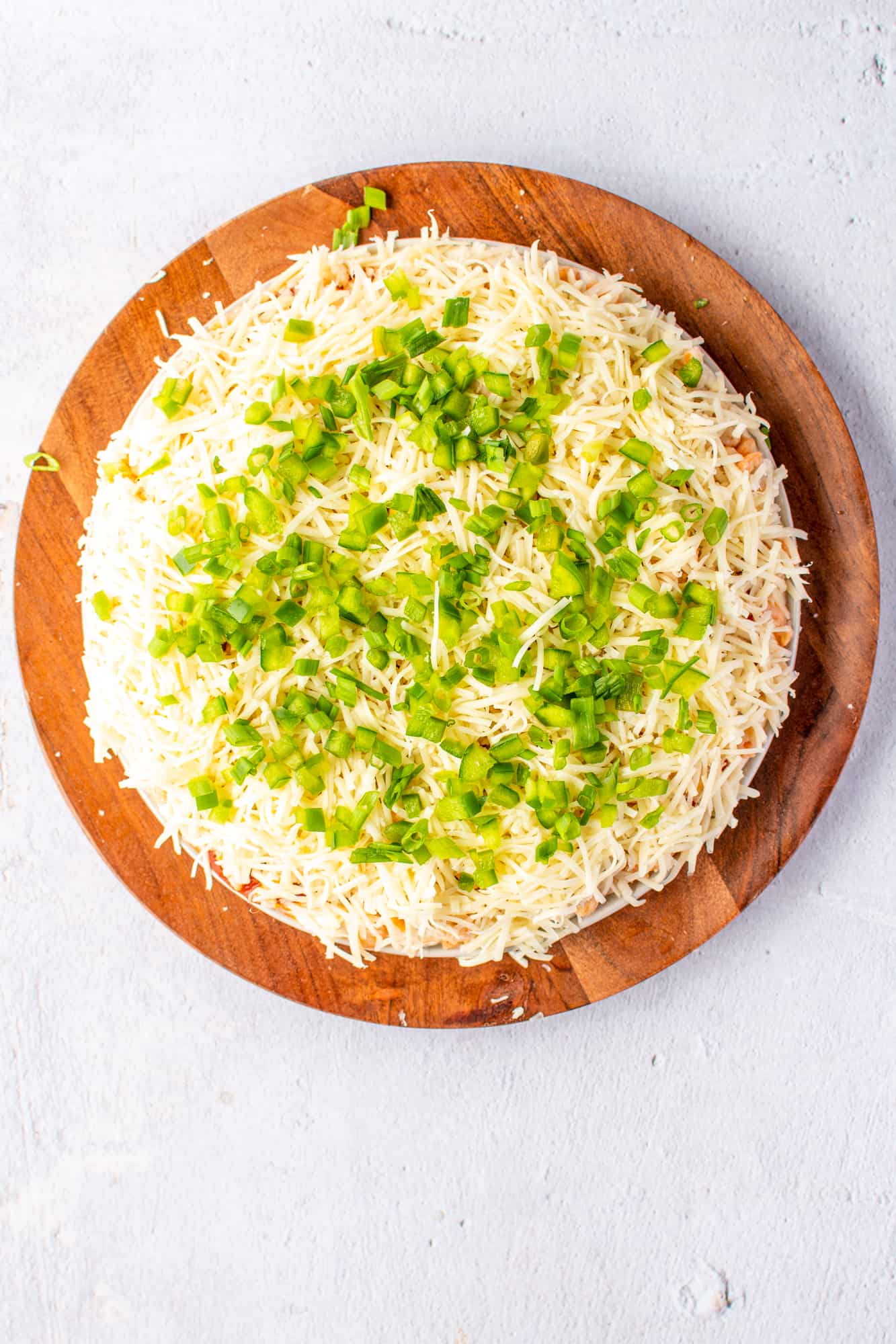 shredded mozzarella, green peppers and green onions on top of seafood layers of the dip.