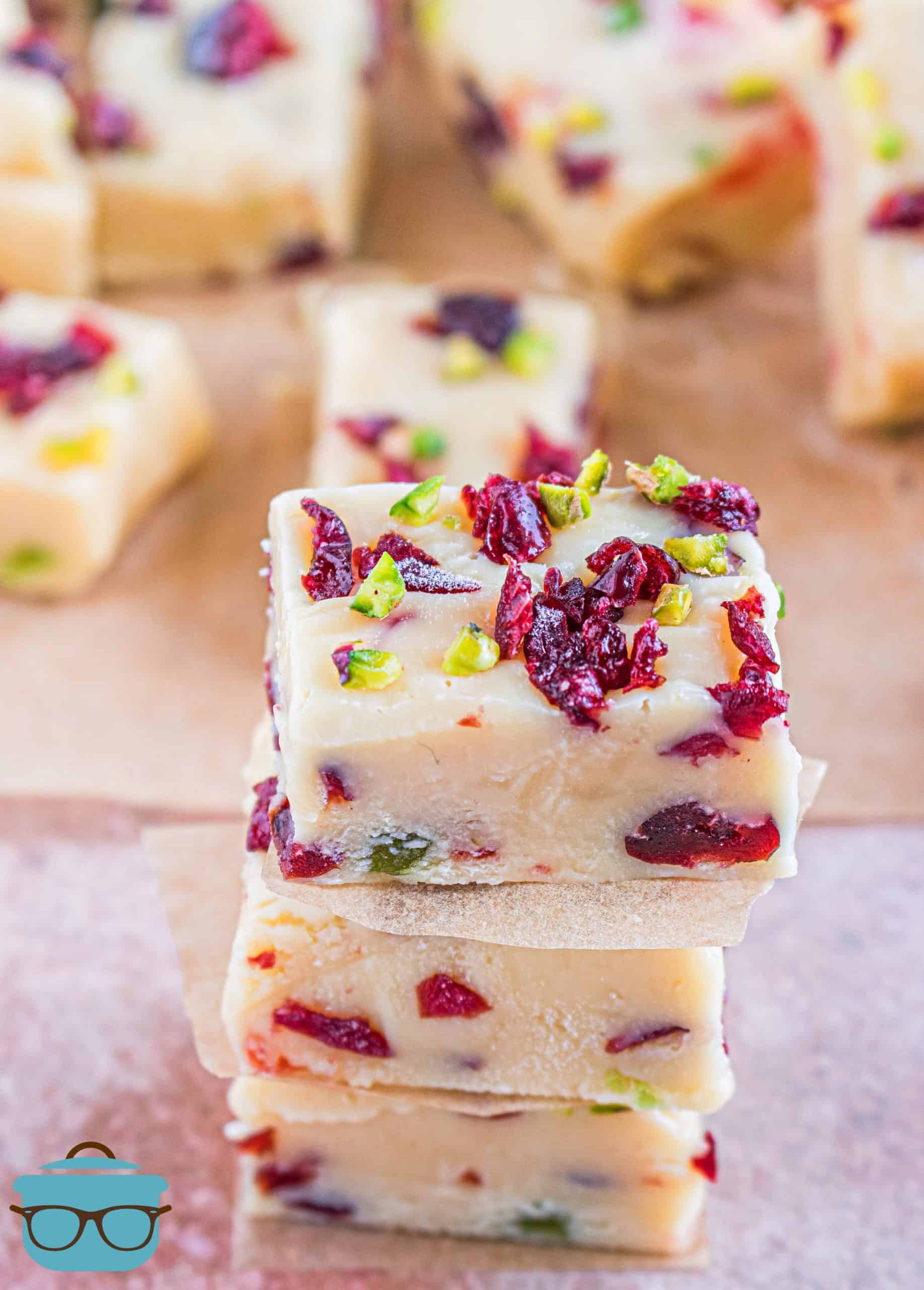 pieces of White Chocolate Cranberry Fudge shown stacked with pieces of fudge in the background.