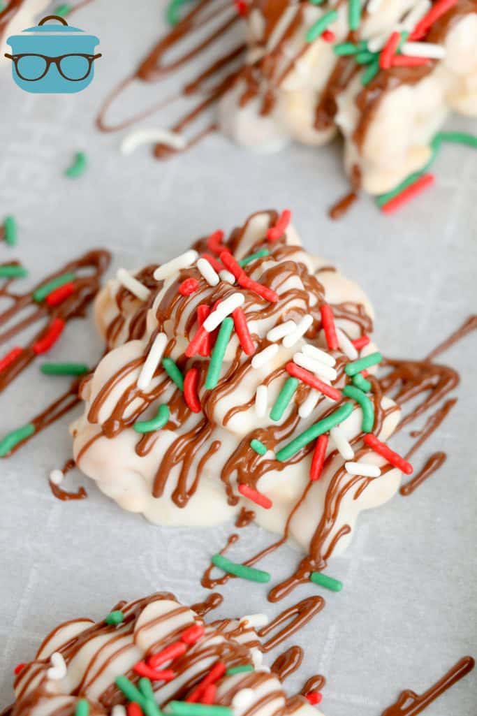 close up of chocolate peanut cluster with red and green sprinkles.