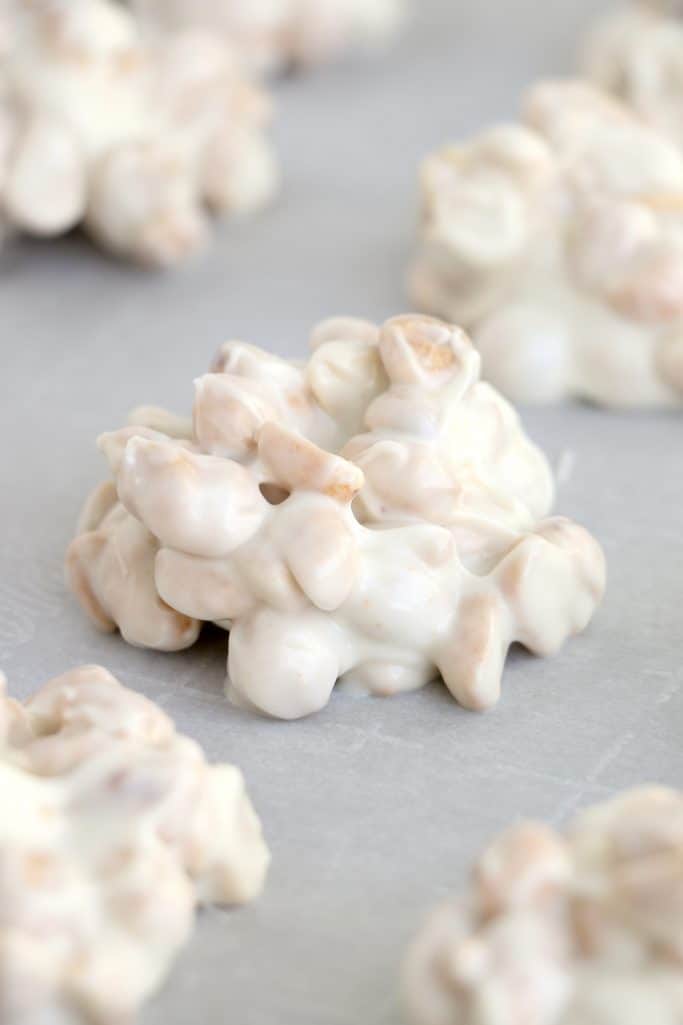 white chocolate peanut cluster shown on parchment paper.