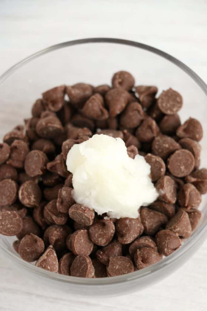 milk chocolate chips and coconut oil shown in a small clear bowl.