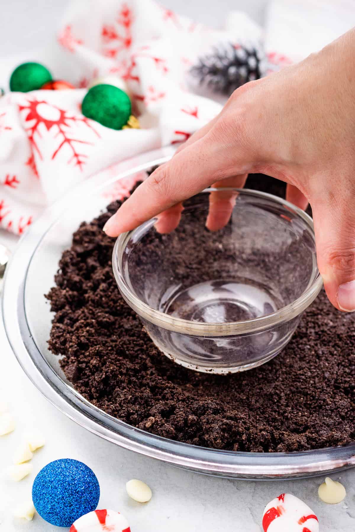 pressing Oreo cookie crumb mixture into the bottom of a clear glass pie plate.