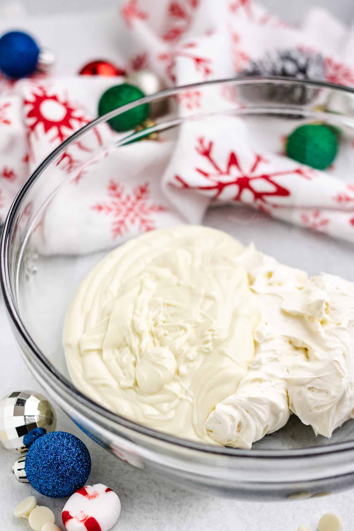 melted white chocolate and creamy cream cheese in the bottom of a clear mixing bowl.
