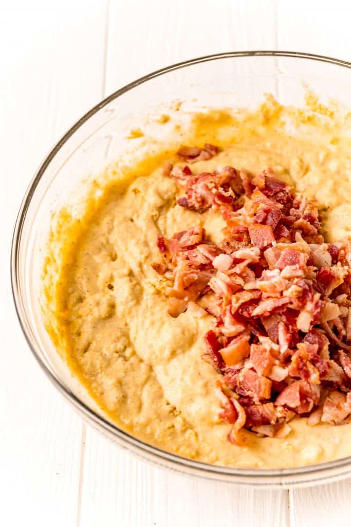 chopped bacon added to cornmeal batter in a bowl