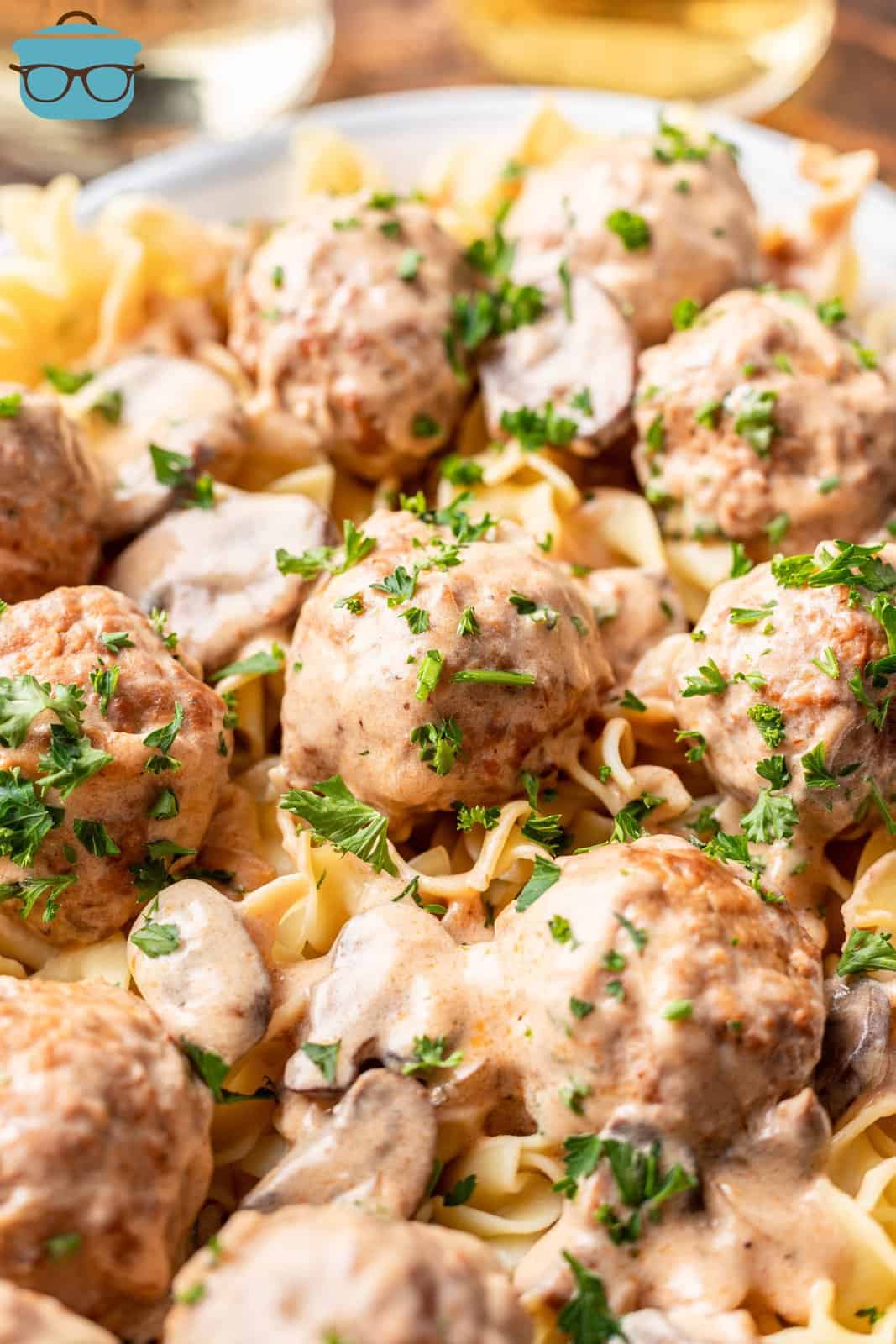 closeup photo of meatball stroganoff served over egg noodles on a white plate. 