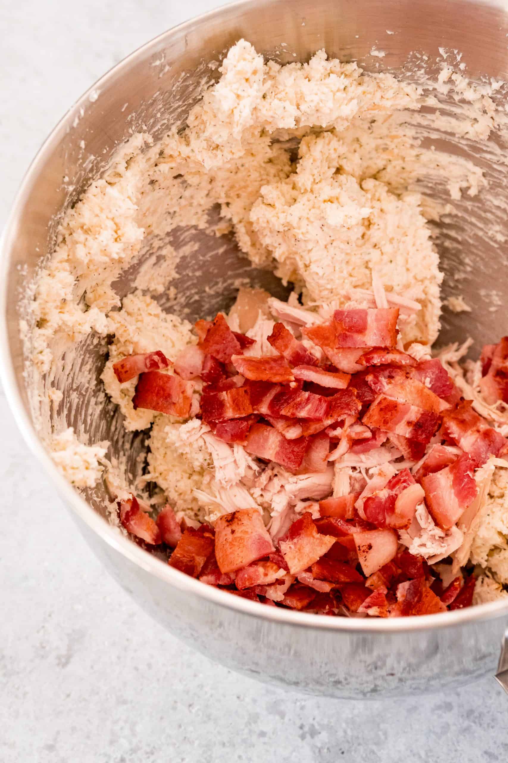 Bacon added to cream cheese, cheese and seasoning mixture.