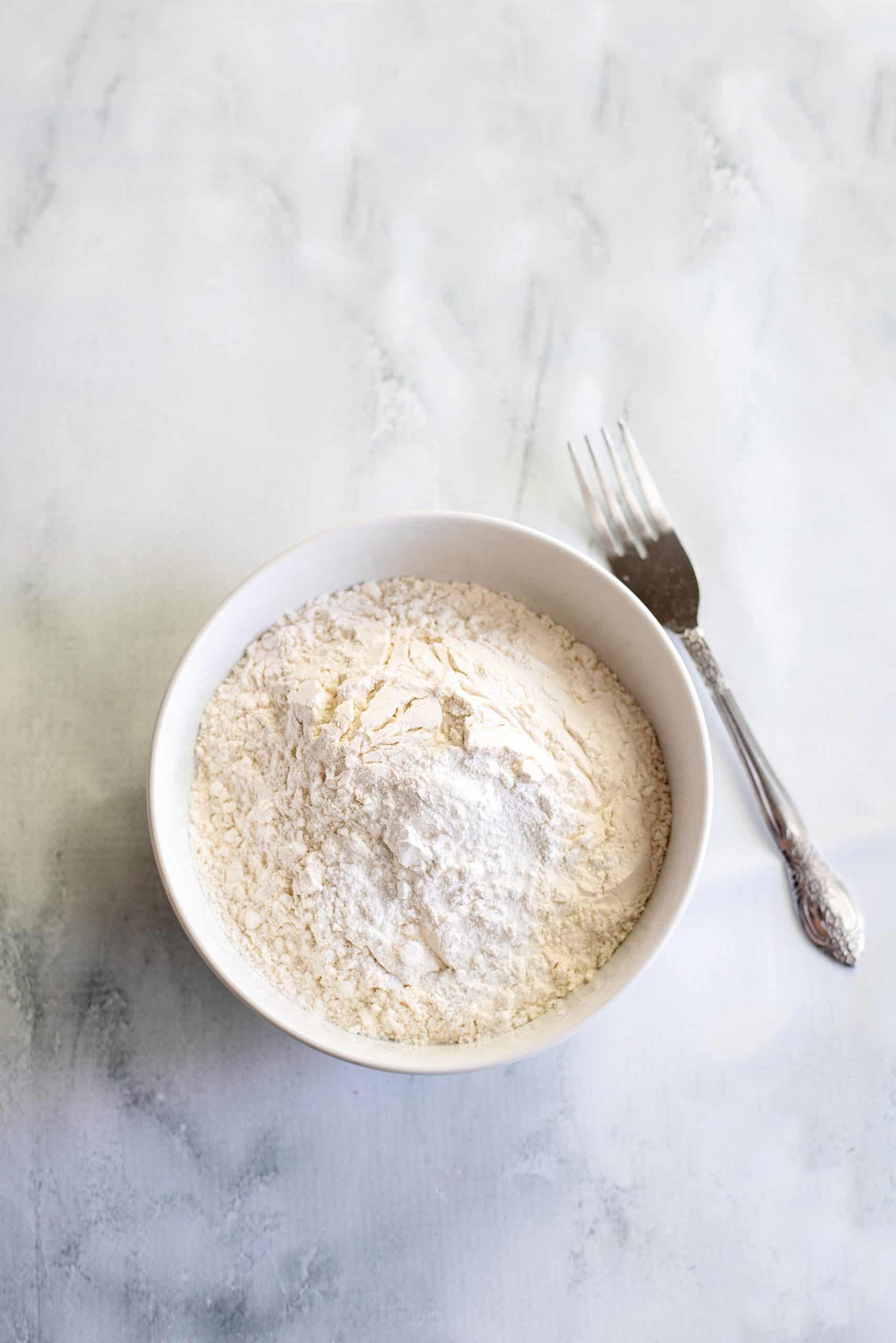 Flour, baking powder and salt in white bowl.