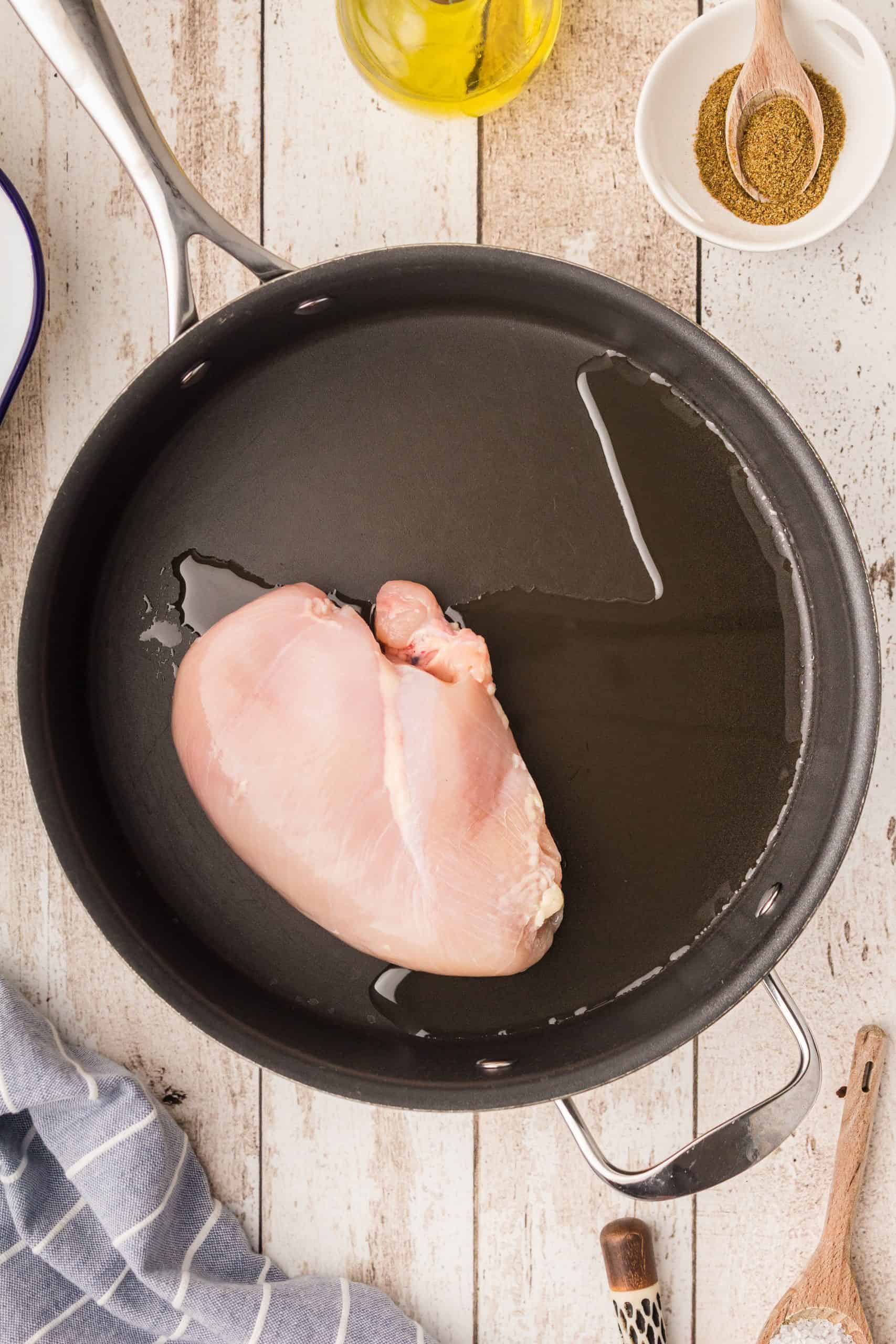 Chicken cooking in oil in pan.
