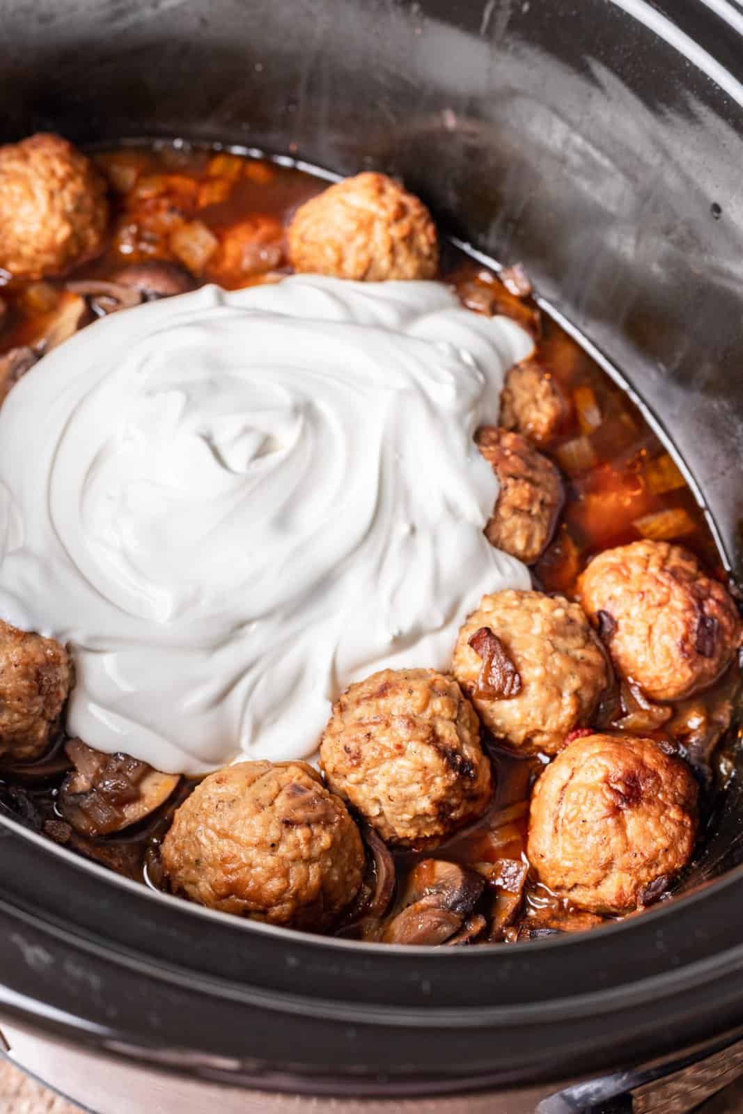 sour cream added to cooked meatballs in slow cooker. 