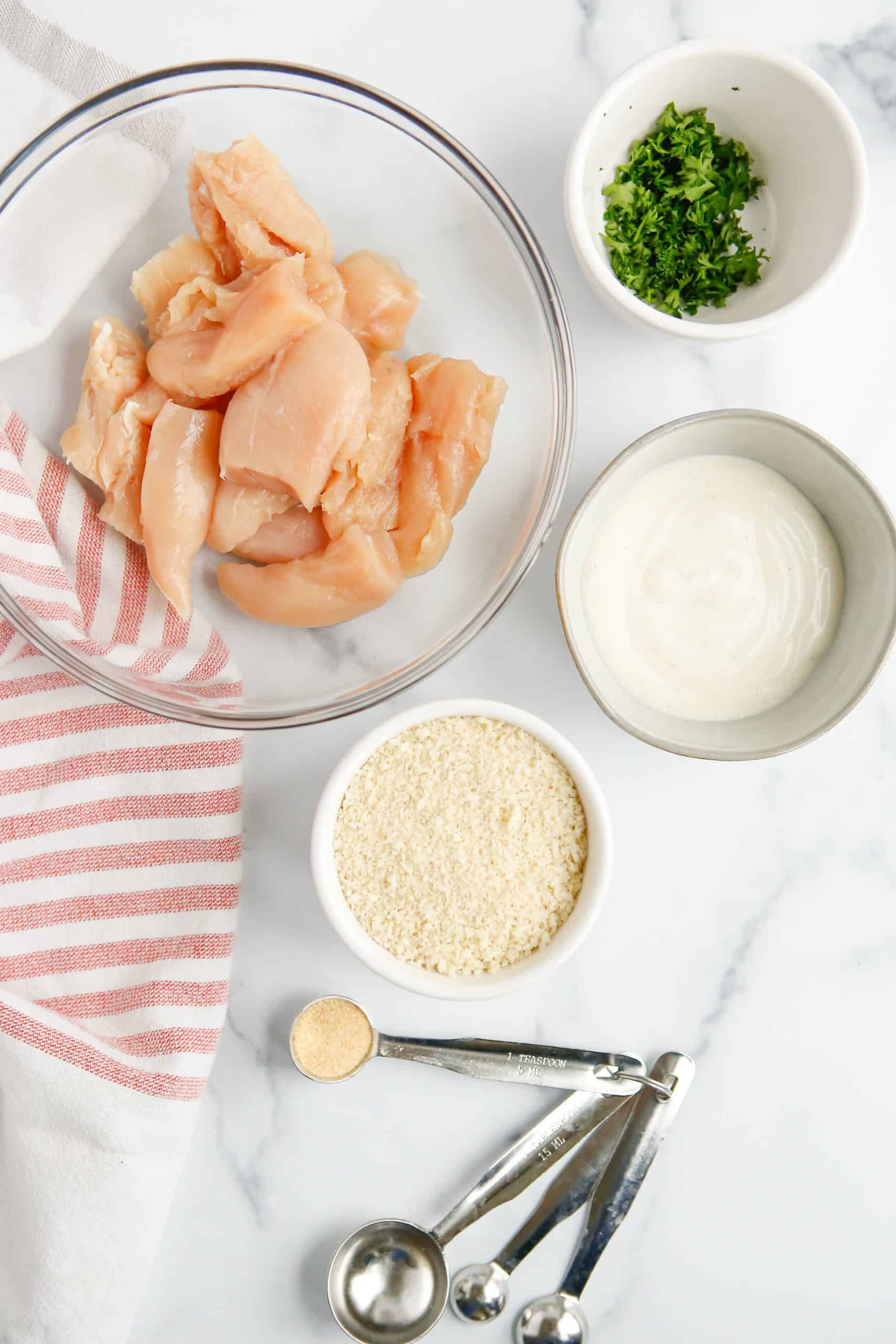 Ingredients needed to make Easy Baked Ranch Chicken Nuggets: diced chicken breasts, Panko breadcrumbs, ranch dressing, parsley and garlic powder.