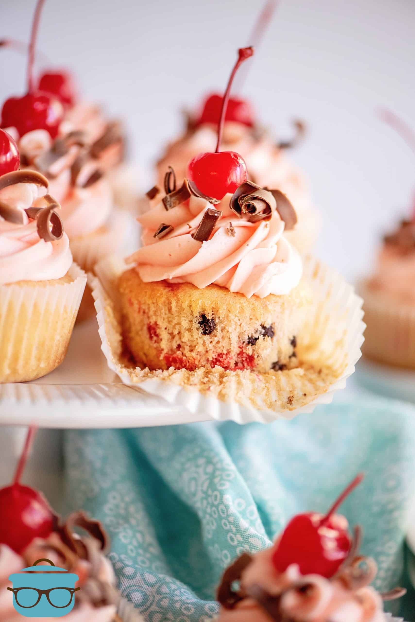 Cherry Chocolate Chip Cupcakes on cake stand with one liner pulled down.