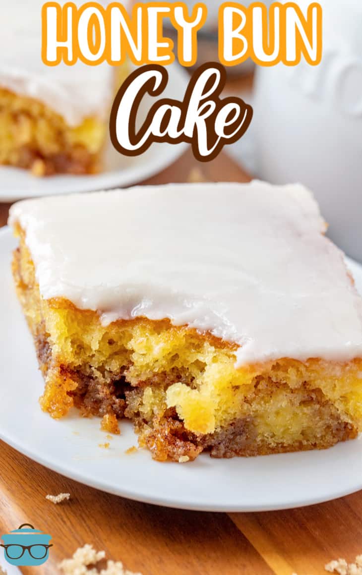 Easy Glazed Honey Bun Cake recipe from The Country Cook, slice of cake shown on a small round white plate with a small bottle of milk in the background.